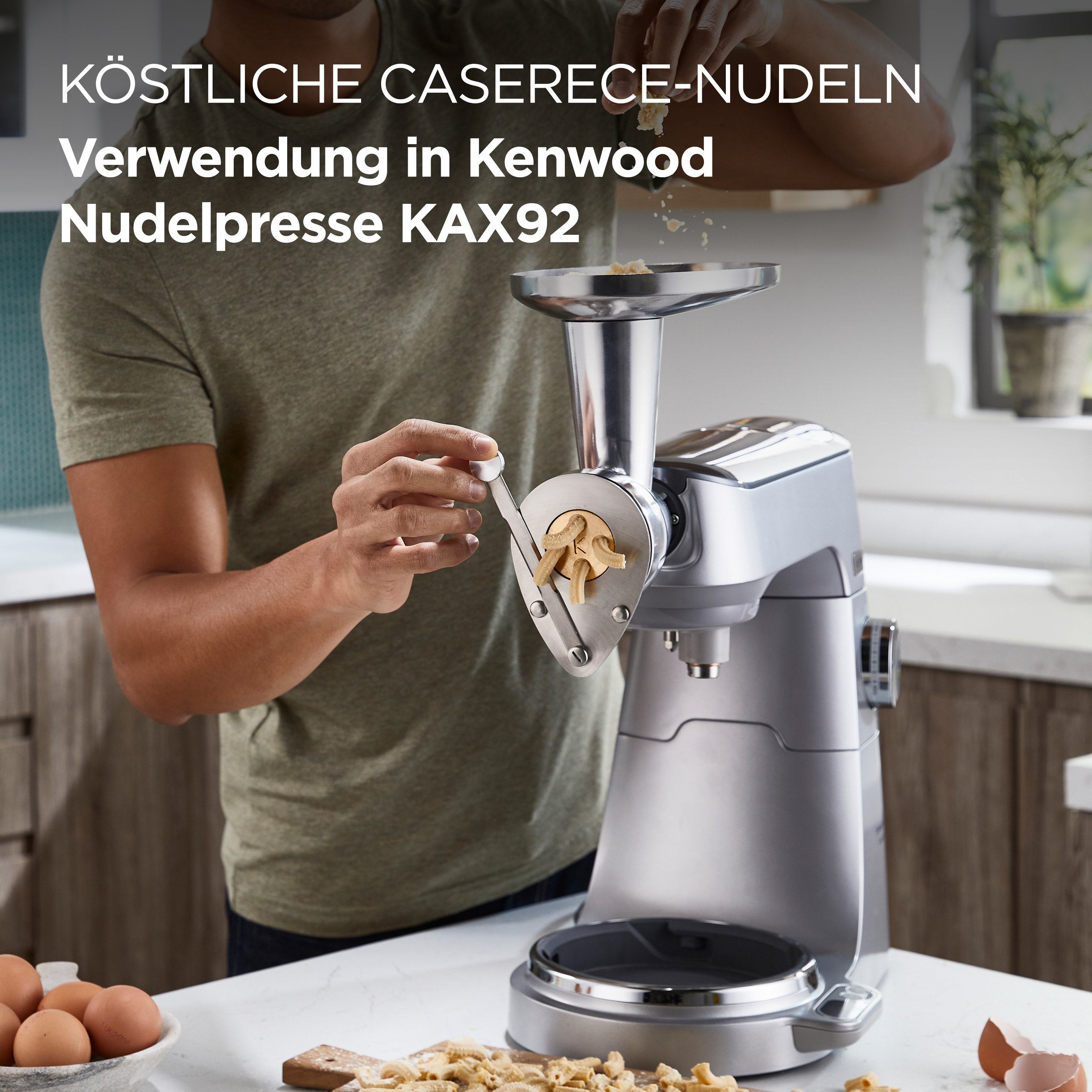 Eine Person gibt Mehl in eine Nudelmaschine, Nudeln und Eier auf dem Tisch.
