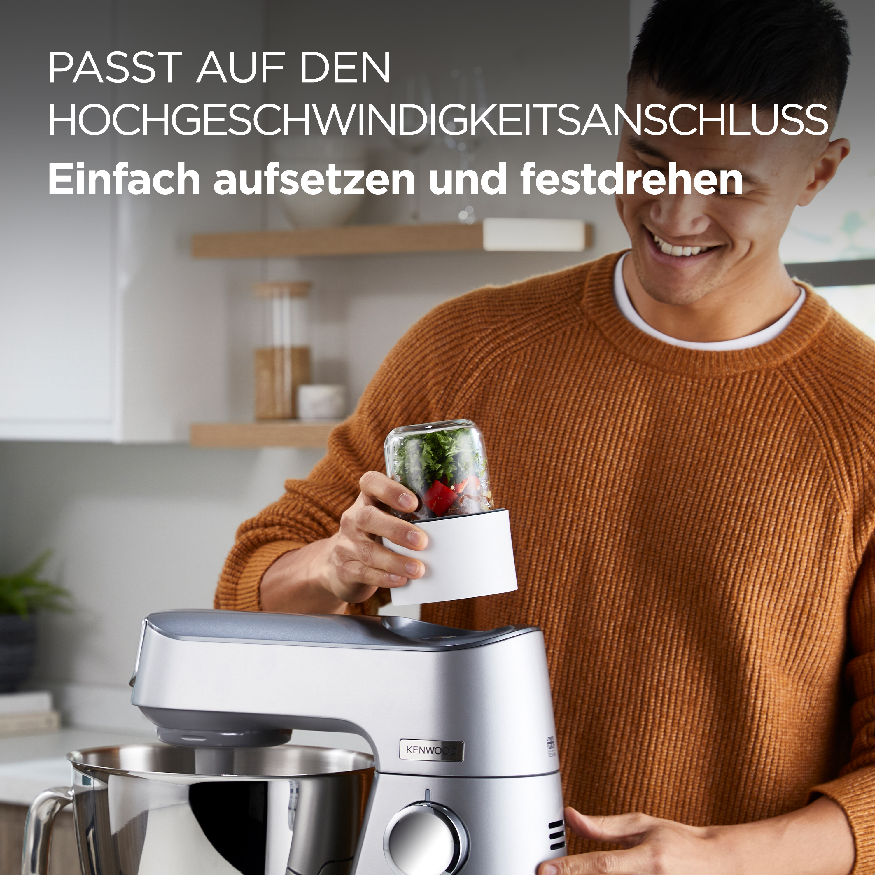Ein Mann benutzt ein silbernes und graues Küchengerät von Kenwood. Er hält einen Behälter.