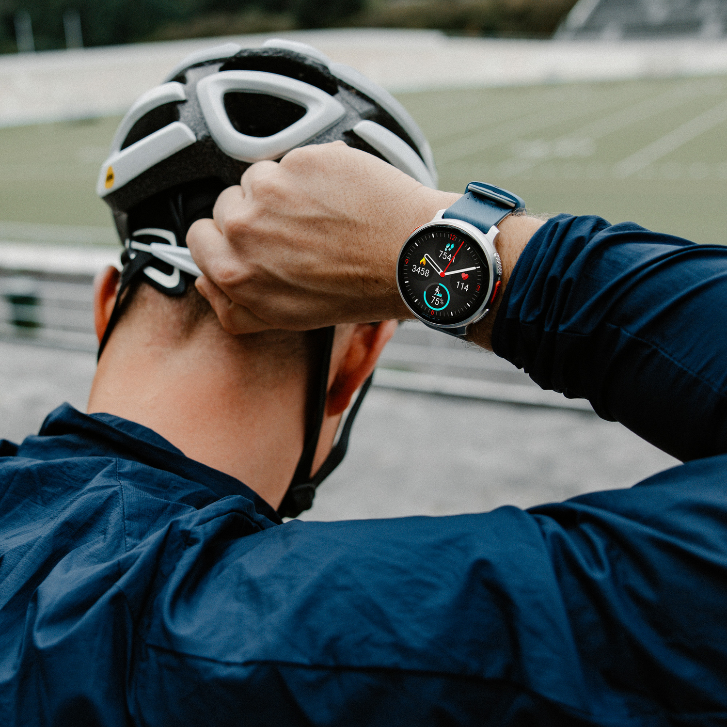 Ciclista con casco, mirando un reloj inteligente. Muestra pasos y frecuencia cardíaca.