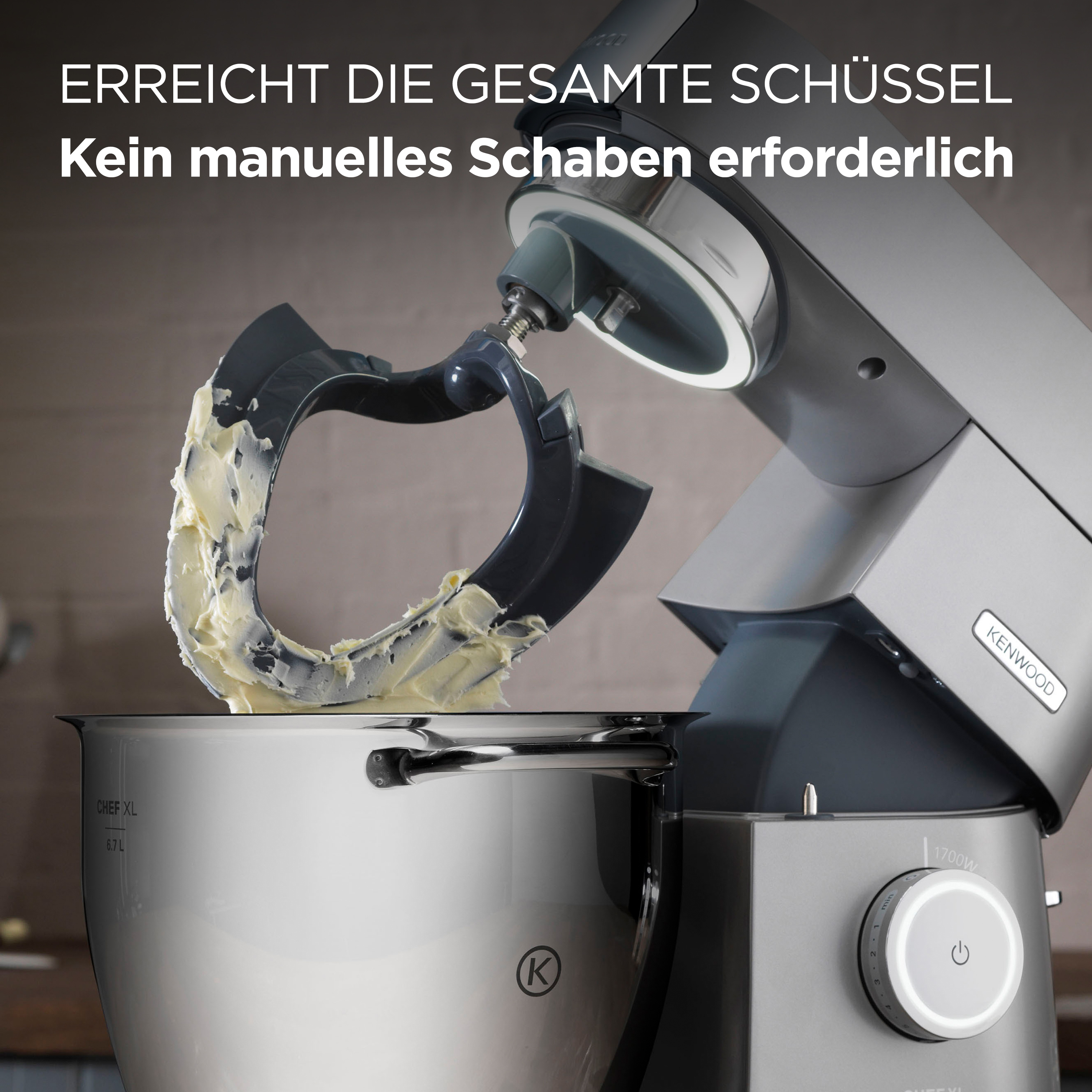 Ein Küchenmixer, der Sahne in einer Stahlschüssel verrührt. Der Text lautet 'Erreicht die gesamte Schüssel' und 'Kenwood'.