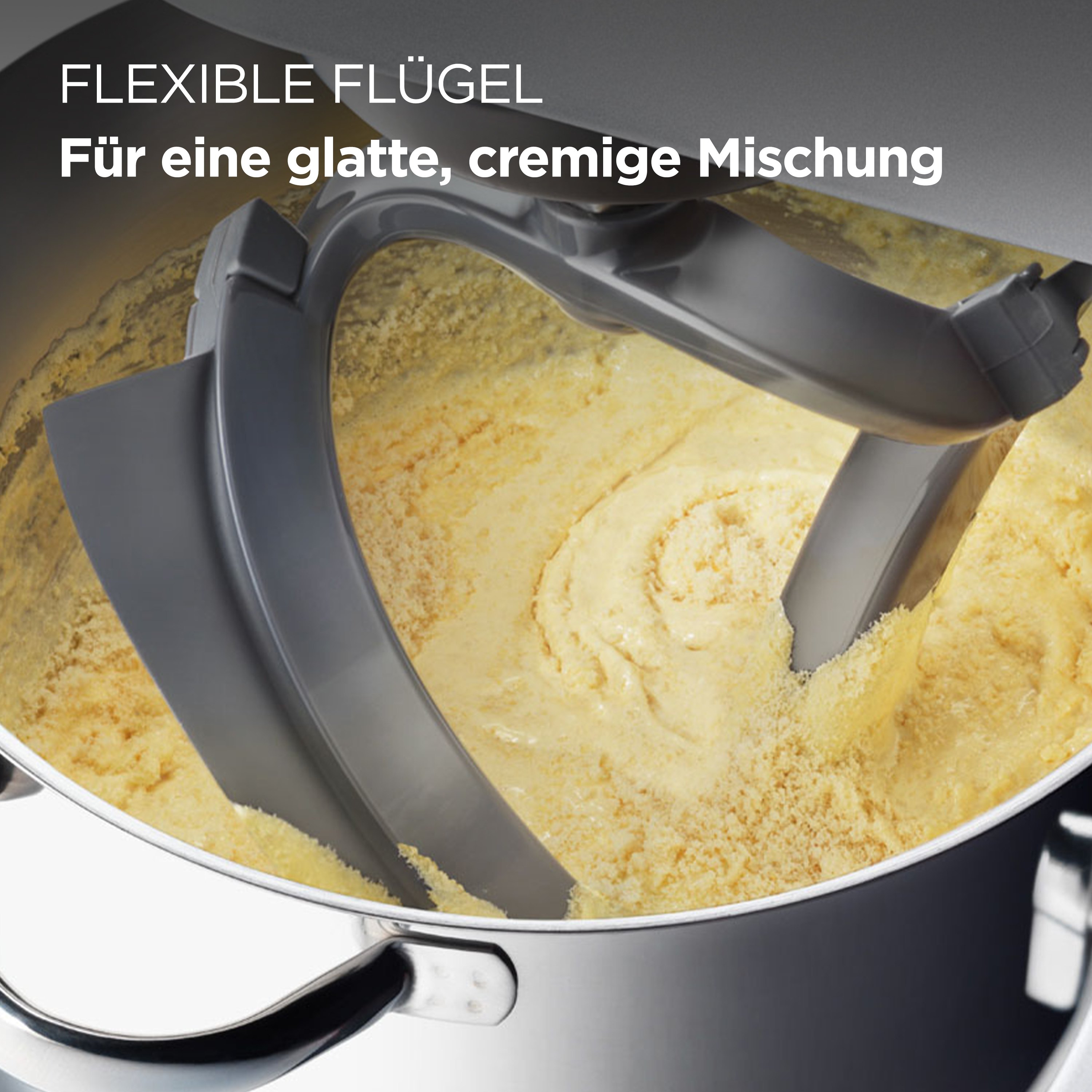 Nahaufnahme einer Mixerschüssel und flexibler Mixerflügel, die gelben Teig mischen. Die Mischung ist strukturiert.