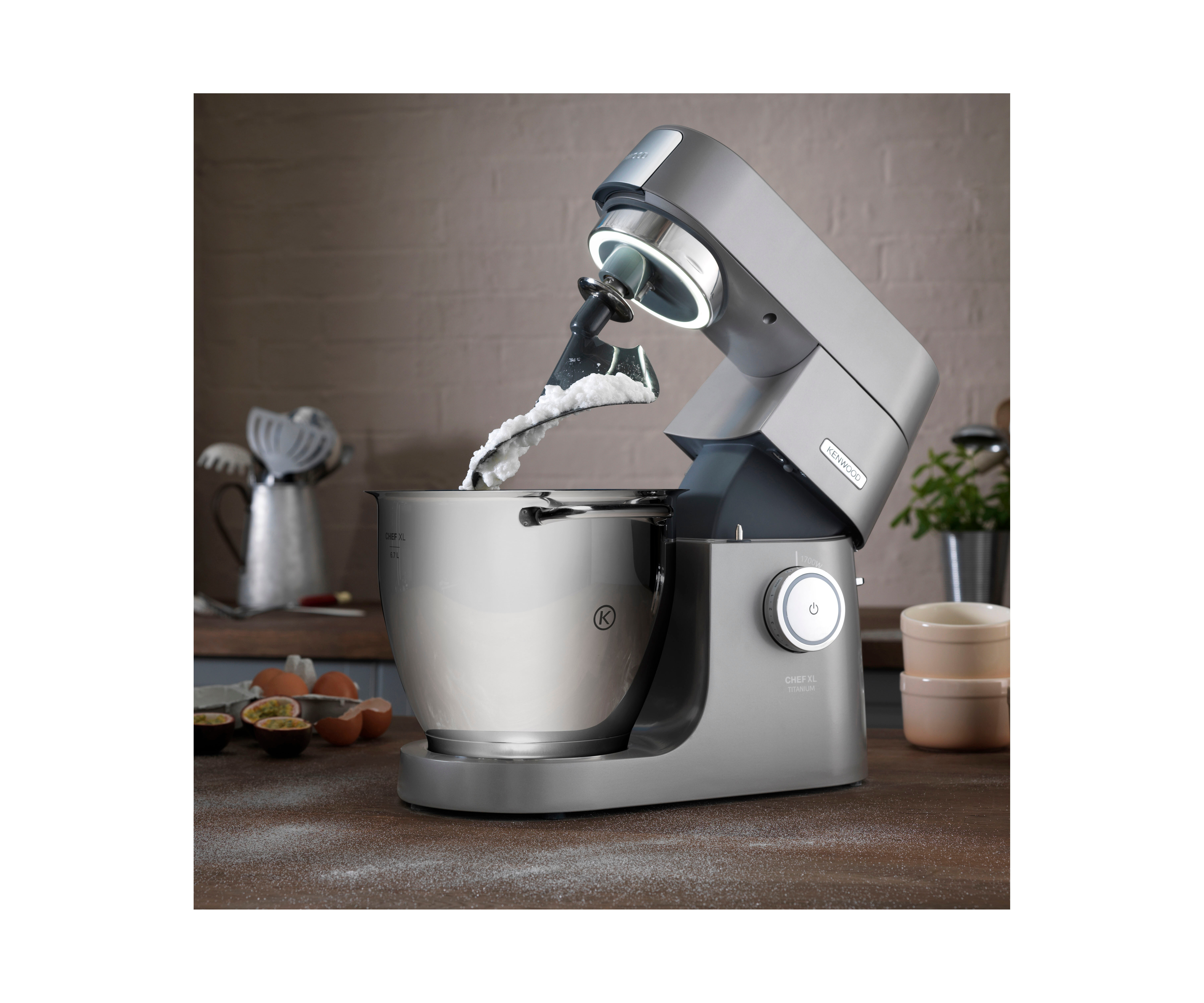 Silberner Küchenmixer mit Schüssel, Zutaten auf der Theke.