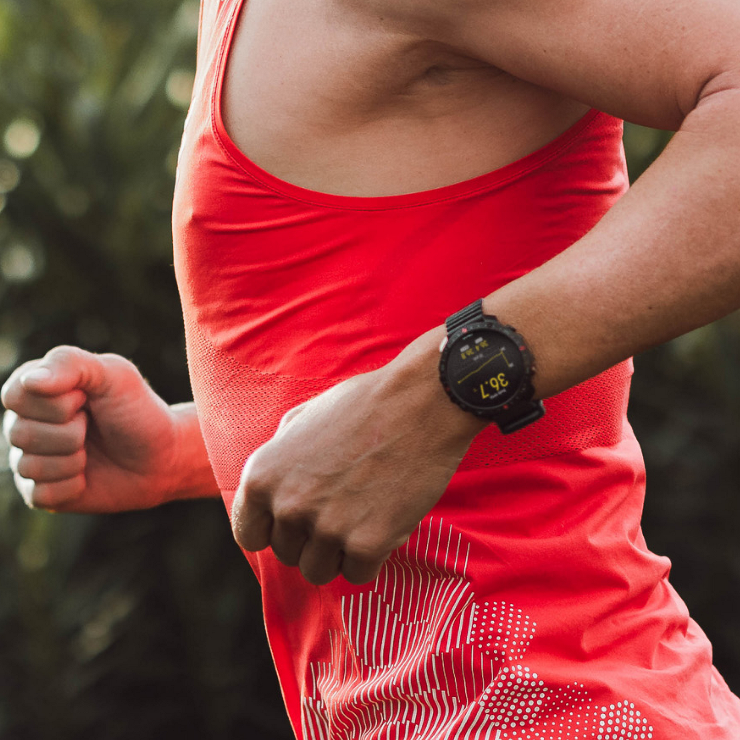 Persona con camiseta sin mangas roja, reloj inteligente negro, corriendo al aire libre.
