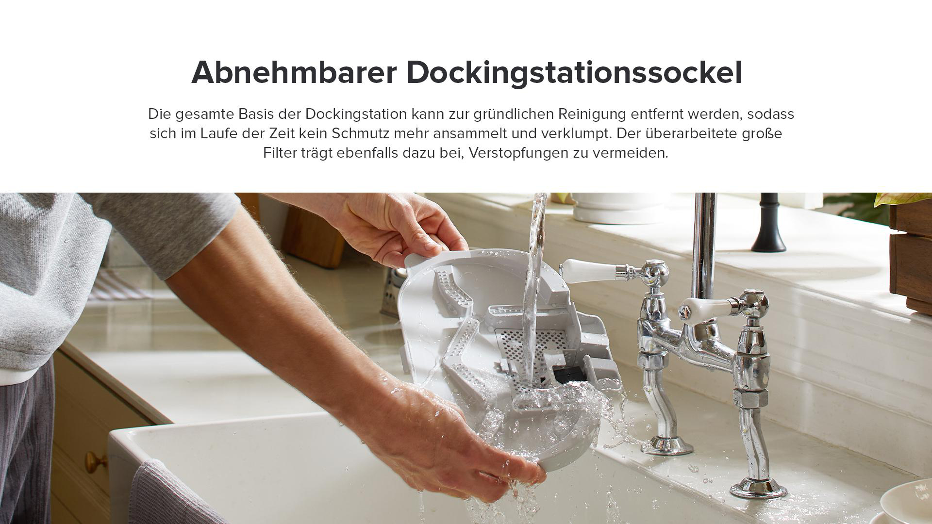Eine Person wäscht eine weiße Dockingstationsbasis unter einem Wasserhahn, Waschbecken im Hintergrund.
