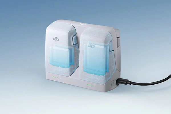 Biała ładowarka do baterii drona z dwoma gniazdami na baterie, portem ładowania i przyciskiem zasilania.