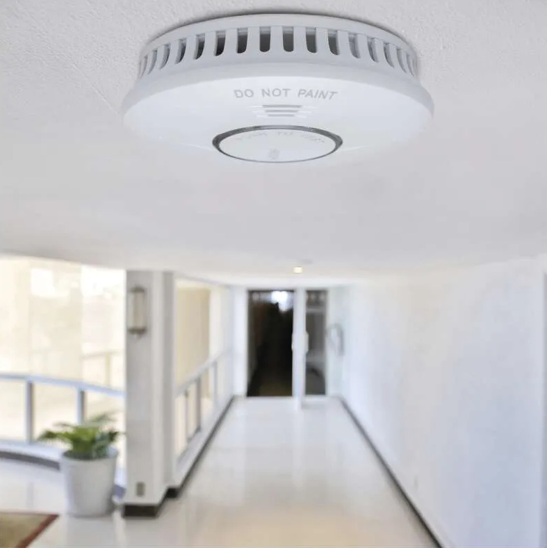 Czujnik dymu na białym suficie, tło korytarza.