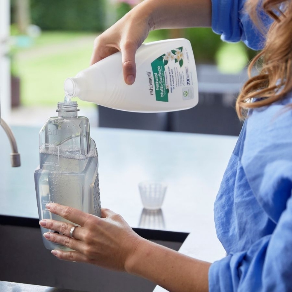 Kobieta wlewa roztwór czyszczący do butelki.