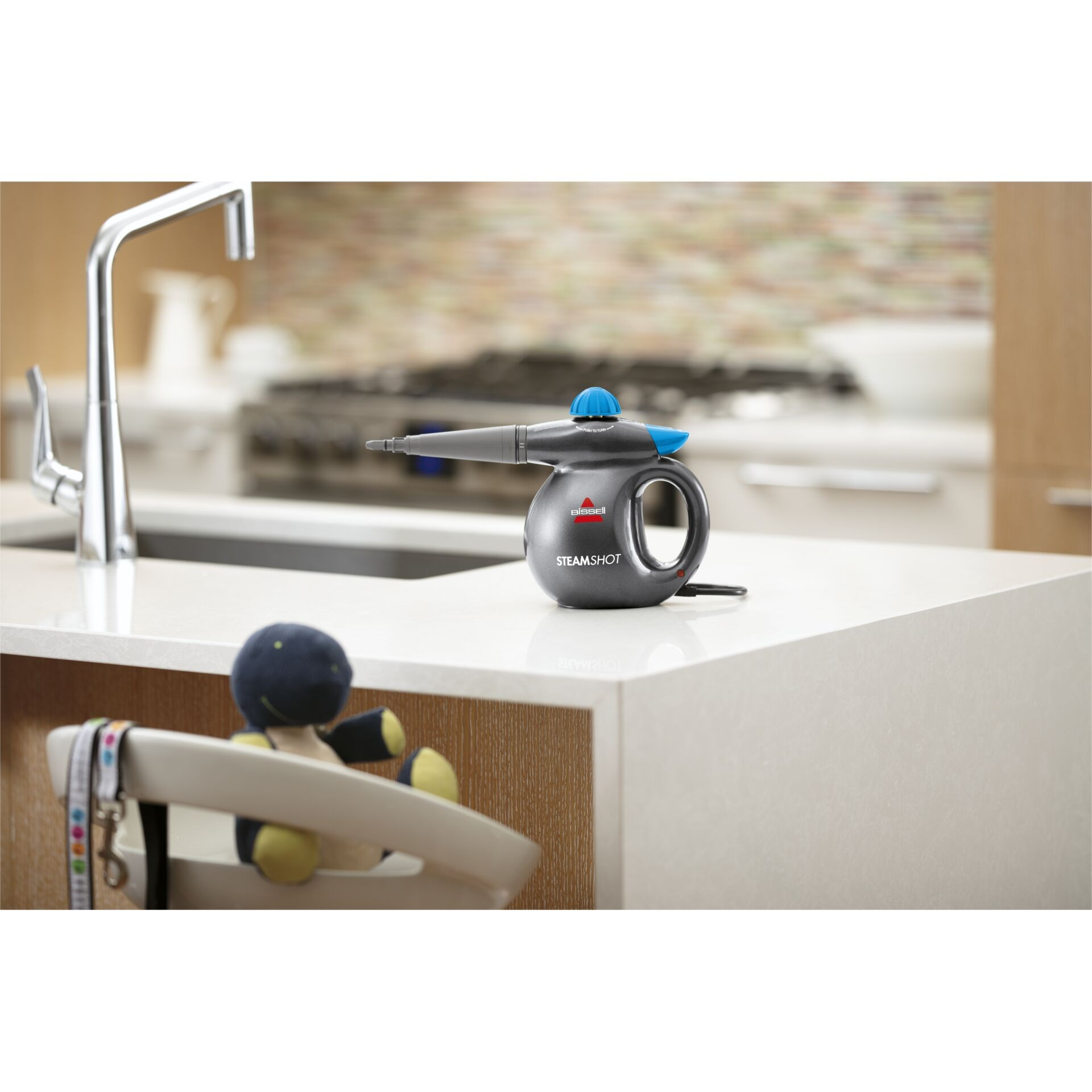 Czarno-szara myjka parowa na białym blacie. Kuchnia w tle.