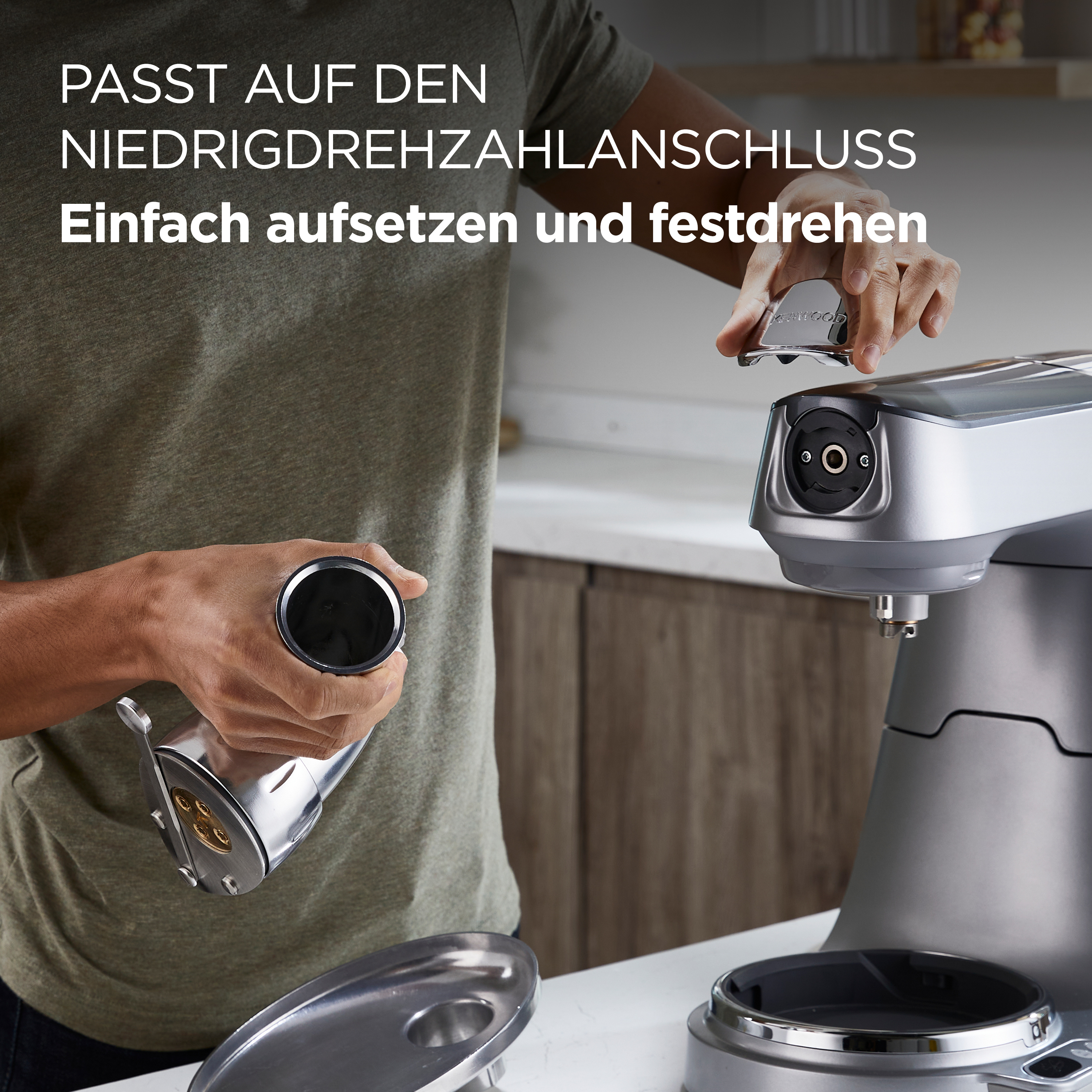 Person, die eine Küchenmaschine zusammenbaut. Silberne Maschine, Hände und Komponenten werden vor weißem Hintergrund gezeigt.