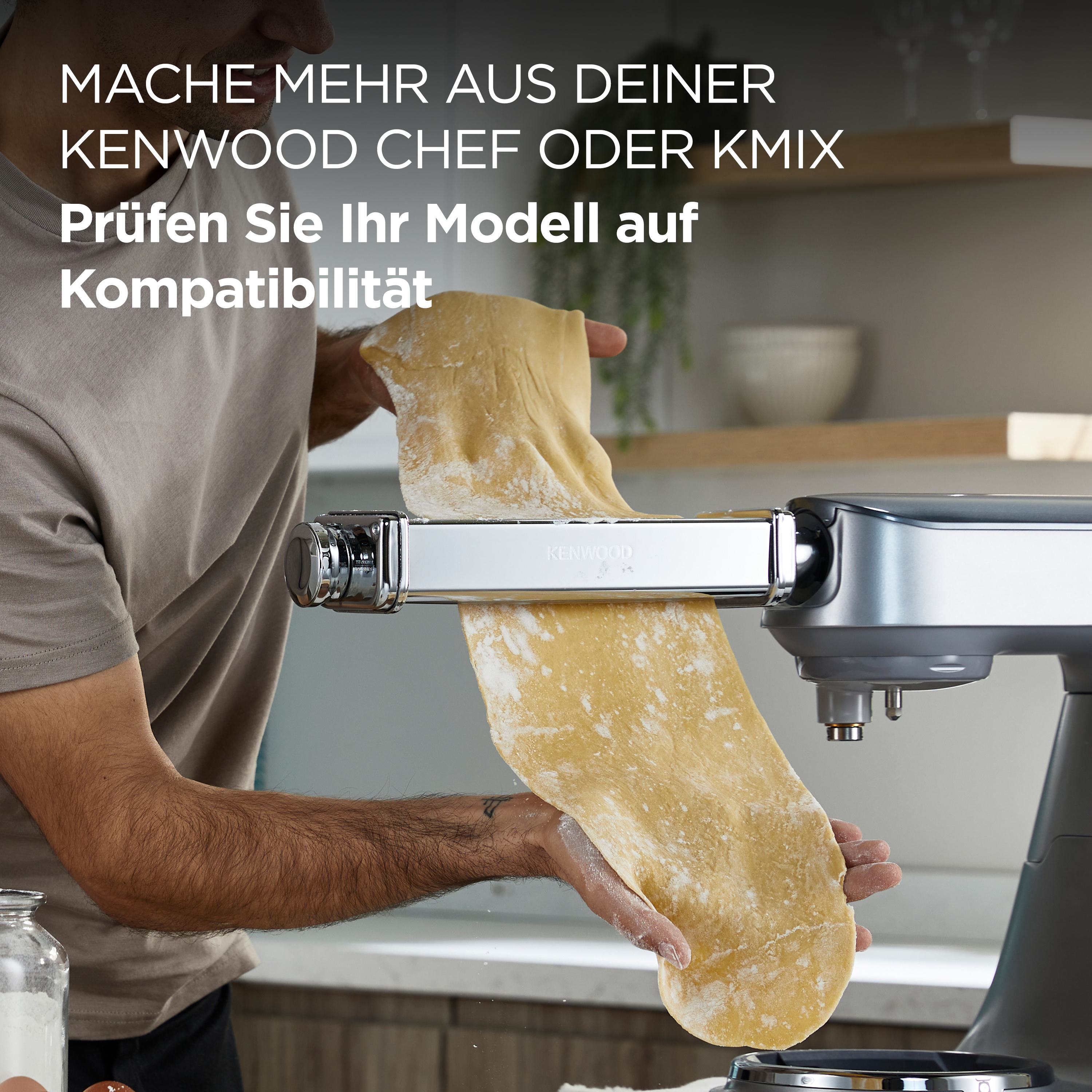Ein Mann benutzt eine Kenwood-Nudelmaschine. Der Mann hält ein Nudelblatt.