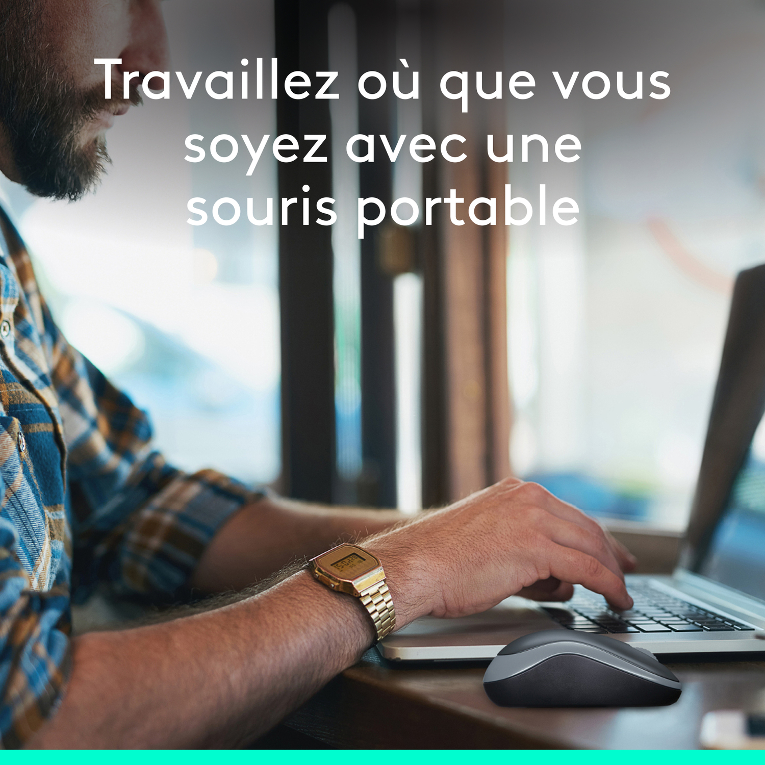 Un homme utilise un ordinateur portable et une souris à une table. Il porte une montre dorée.