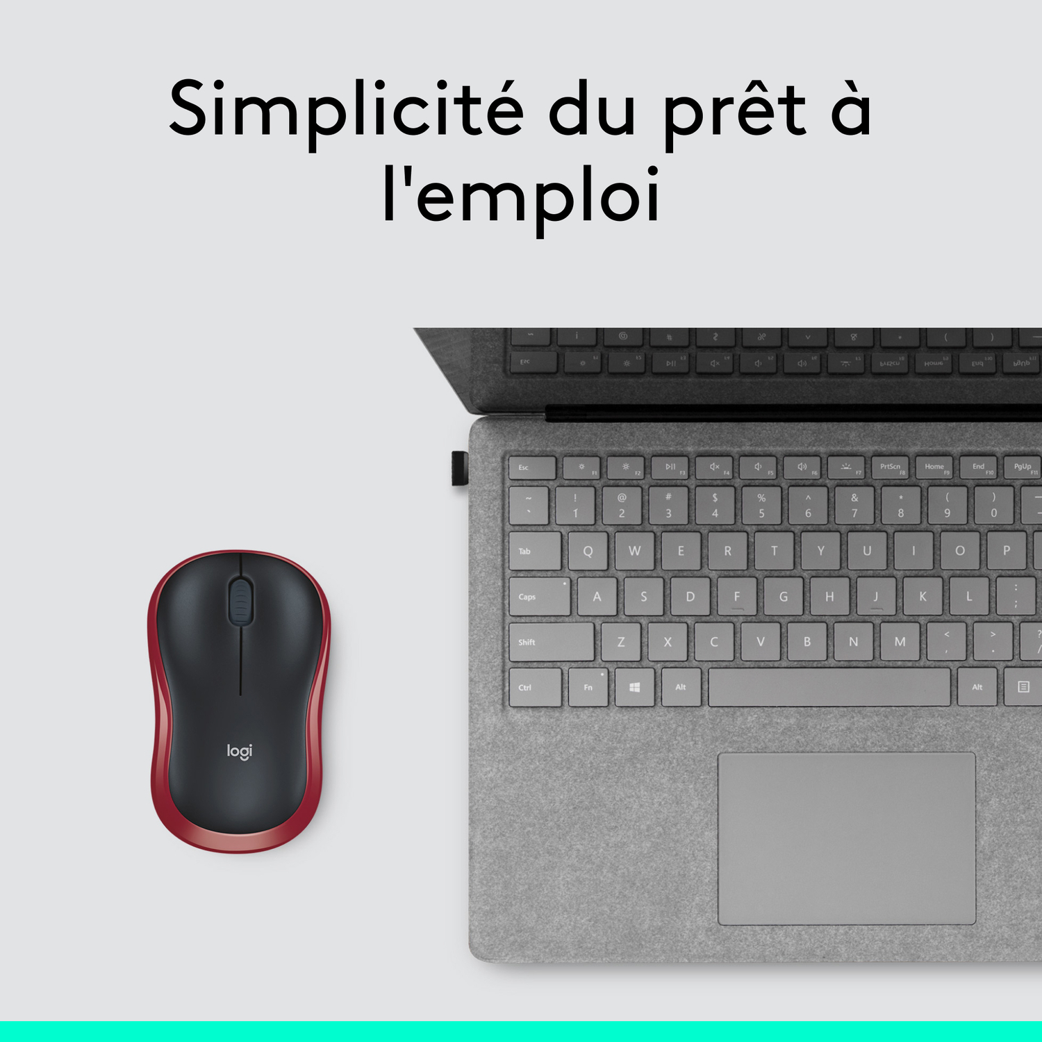 Une souris rouge et noire à côté d'un clavier d'ordinateur portable.