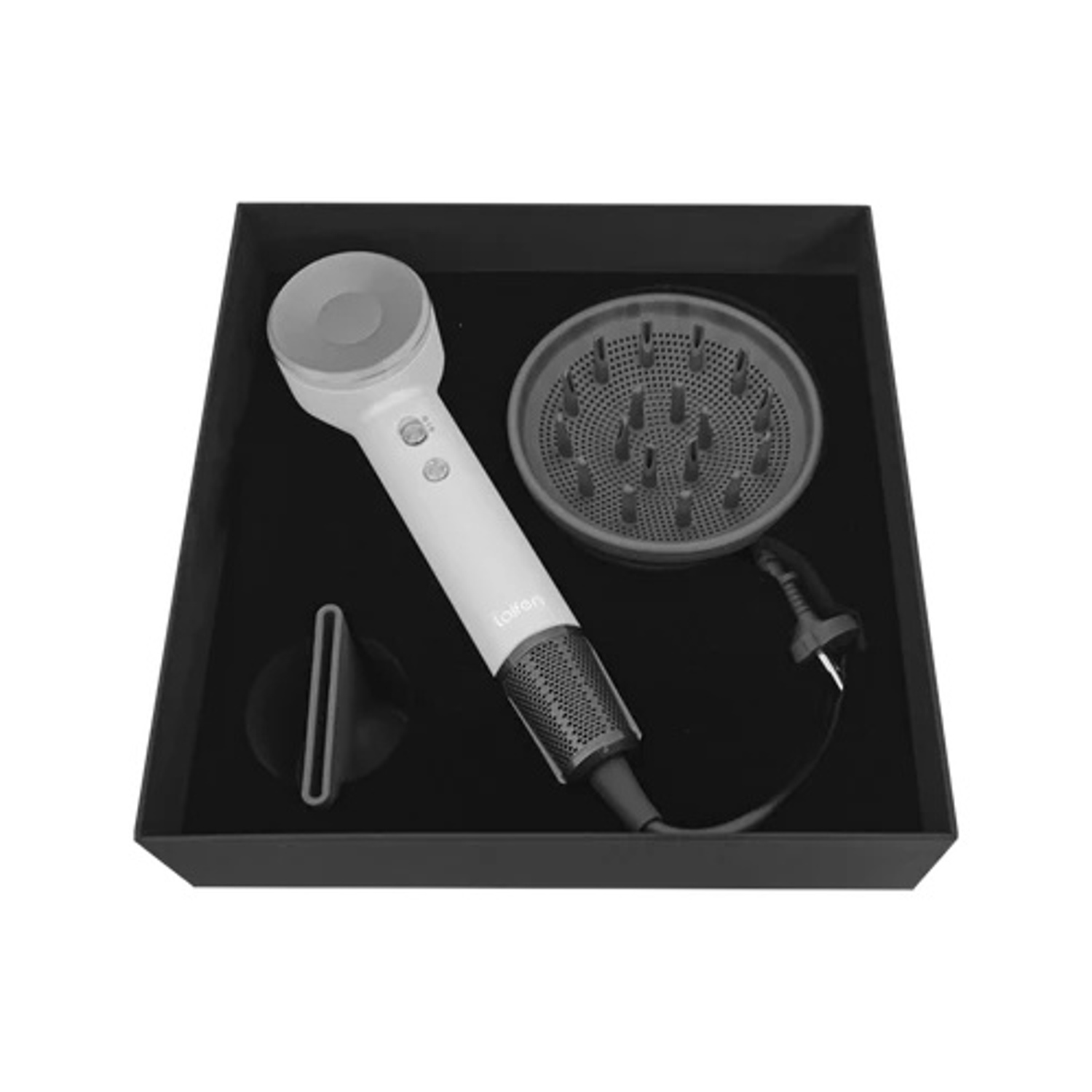 Immagine in bianco e nero di un asciugacapelli e accessori in una scatola.