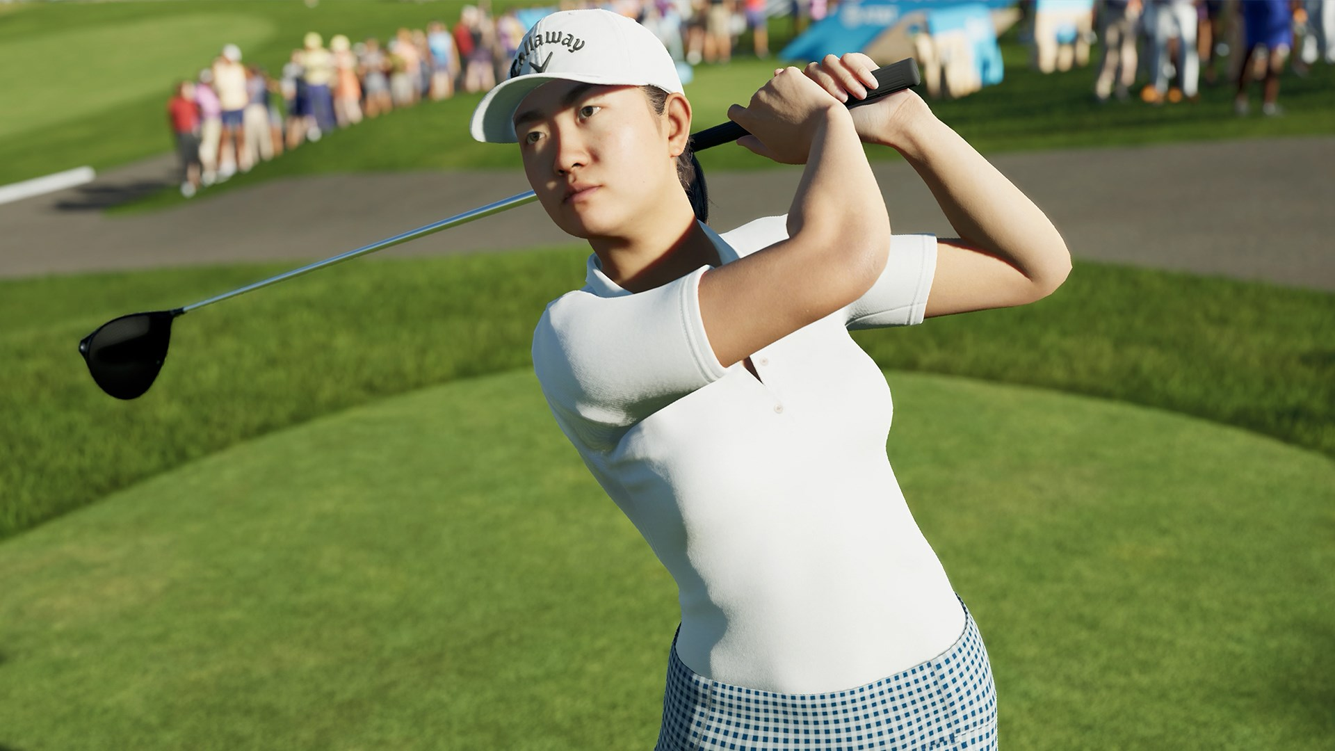 Eine Frau beim Golfschwung, mit einem Callaway-Hut, auf einem grünen Golfplatz.
