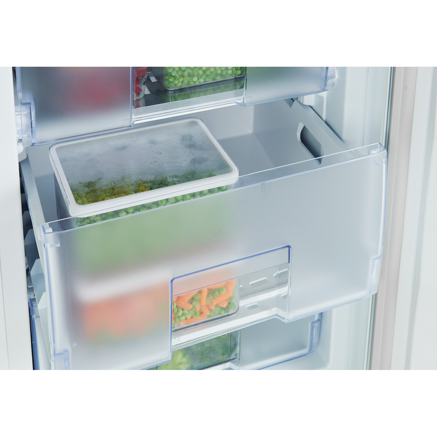 Inside a refrigerator, drawers are filled with vegetables. Containers hold peas and carrots.