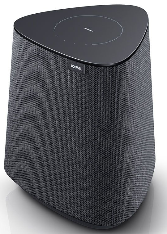 Pokazano głośnik Loewe. Jest ciemnoszary, trójkątny, z siatkowym przodem i panelem dotykowym na górze.