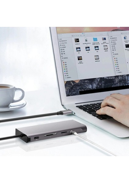 Bir dizüstü bilgisayar, bir USB hub'ına bağlı, klavye ve masada bir fincan.