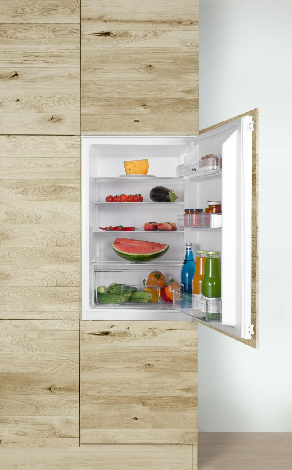 Ein offener Kühlschrank voller frischer Produkte: Tomaten, Wassermelone, Paprika, Gurken und mehr.