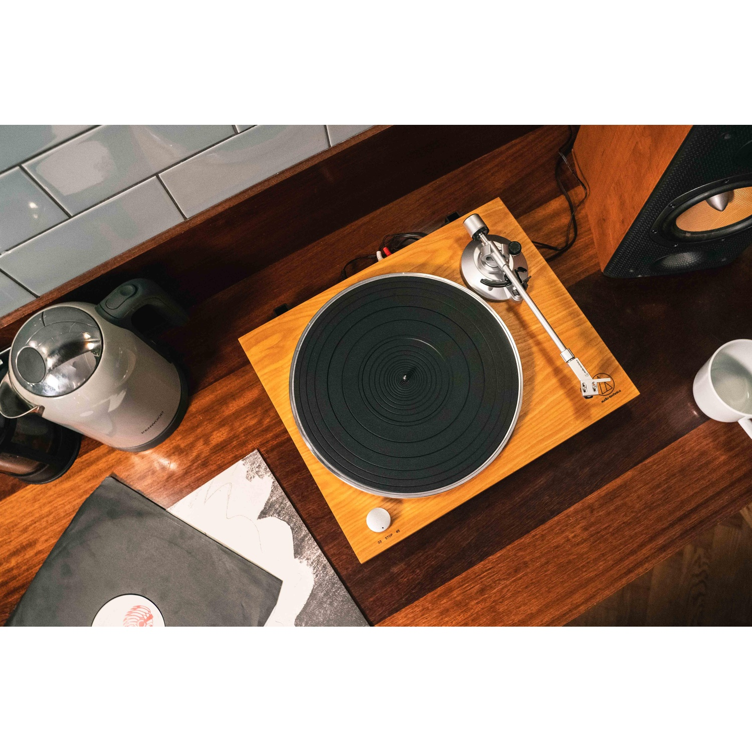 Un giradischi con dischi in vinile. Mobile in legno, dischi e un bollitore.