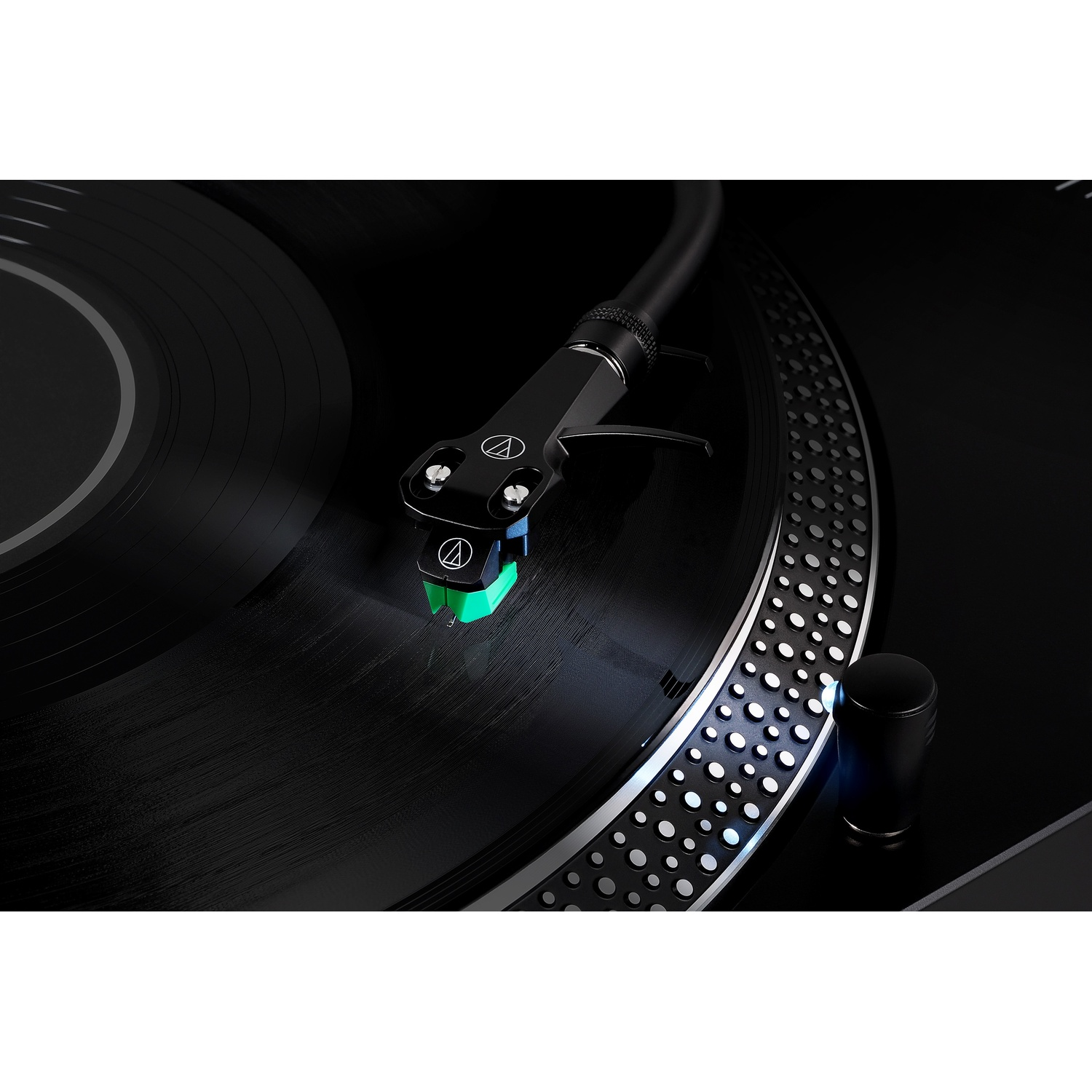 Primo piano di un vinile su un giradischi con un ago verde.