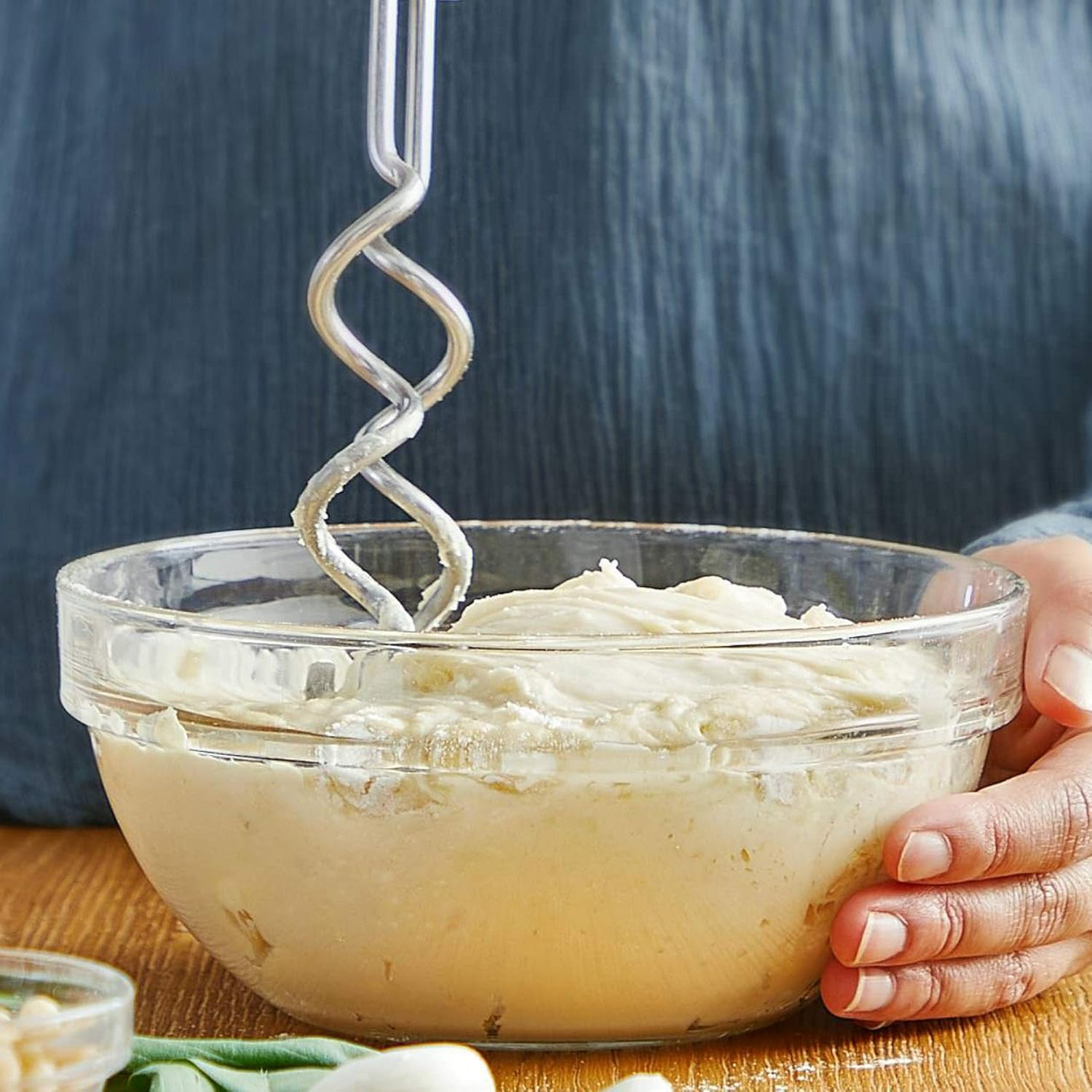 Ręka trzyma miskę z kremową mieszanką. Mieszarka jest w misce.