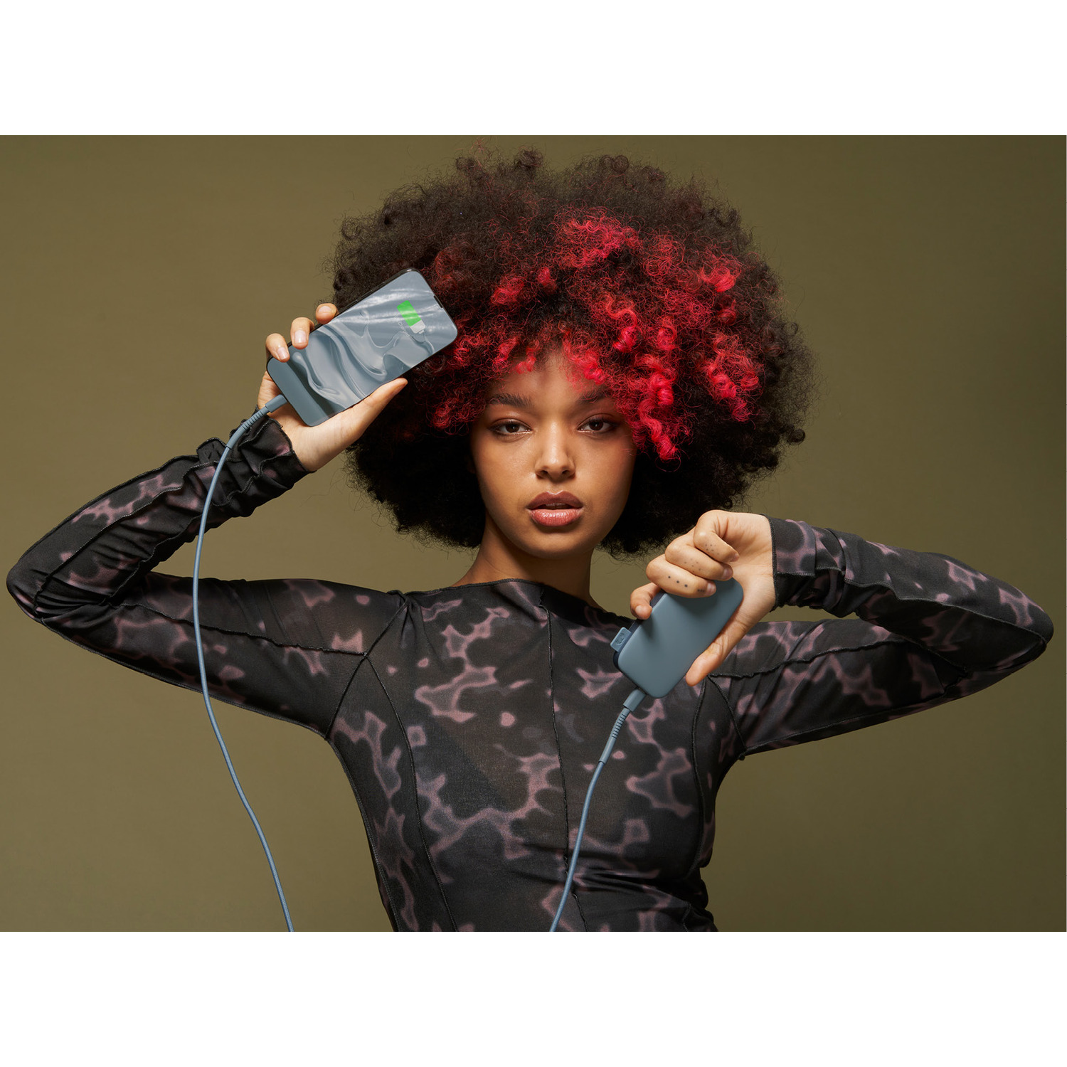 Een vrouw die een telefoon vasthoudt die wordt opgeladen via een powerbank, met rood haar.