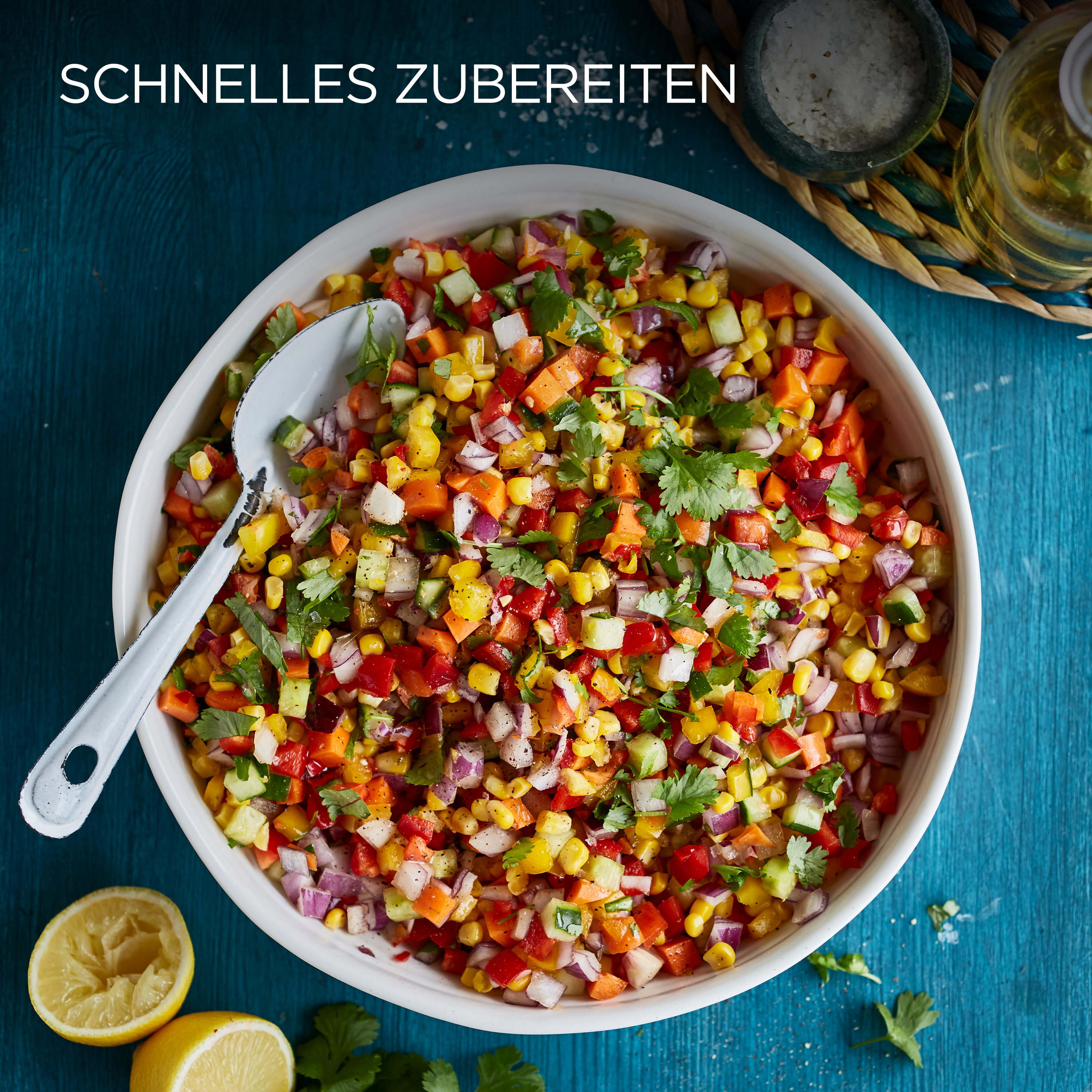 Nahaufnahme von bunter Mais-Salsa in einer weißen Schüssel mit Löffel, auf blauem Tisch, Zitrone in der Ecke.