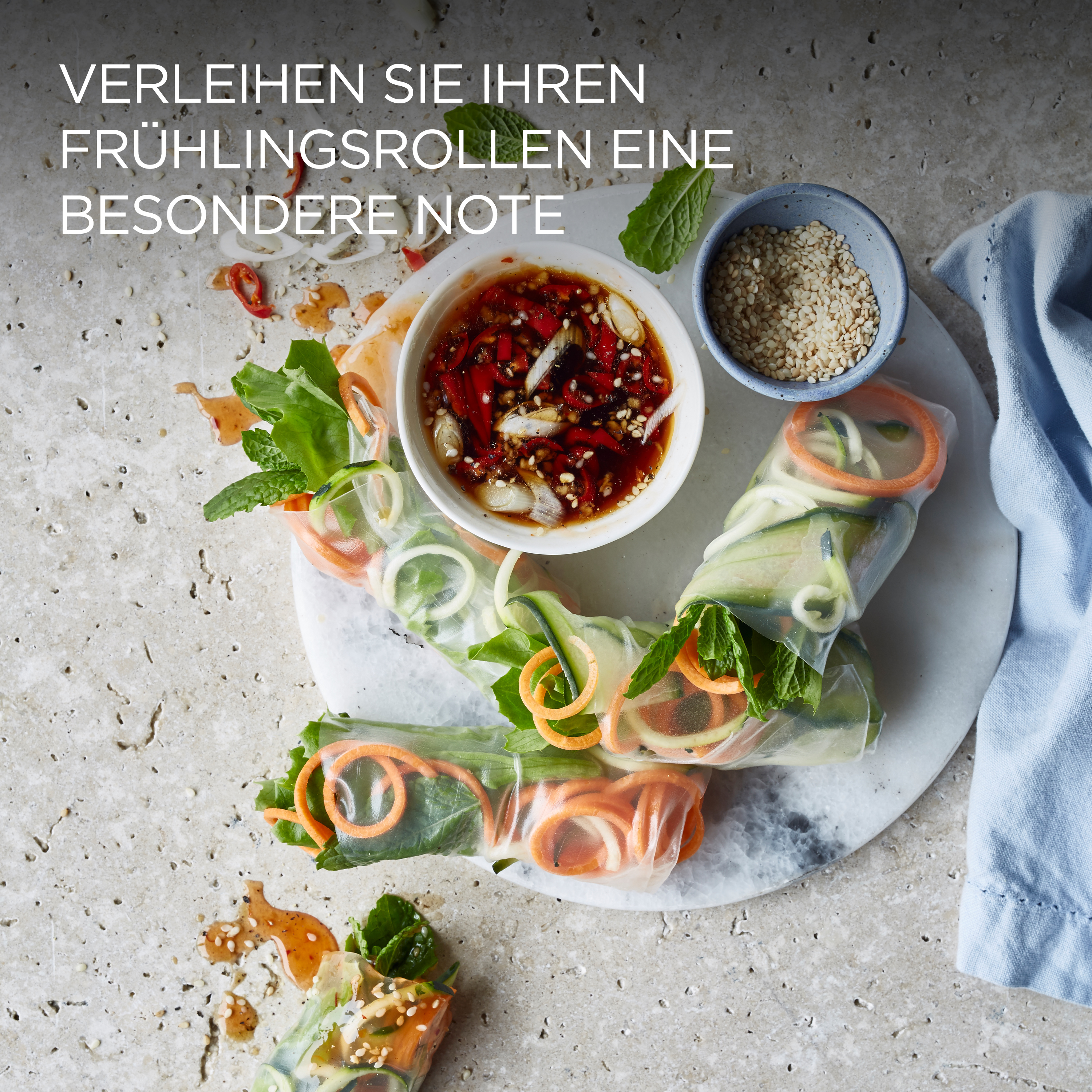 Frühlingsrollen mit Dip-Soße und Sesamsamen auf einem weißen Teller.