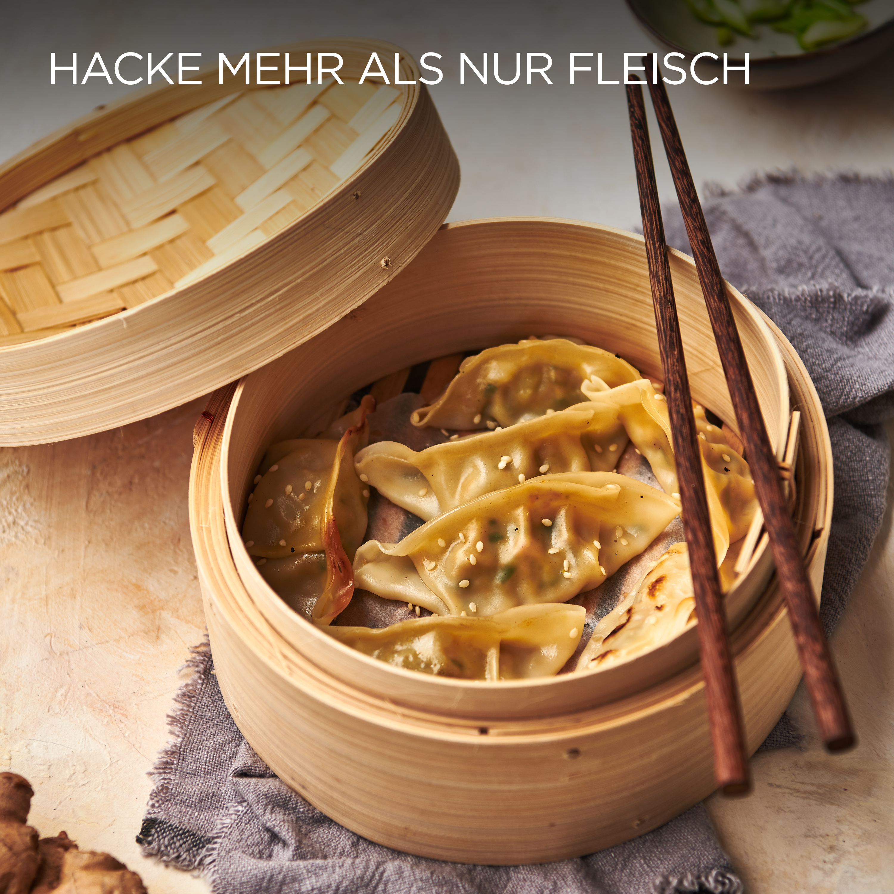 Gedämpfte Knödel in einem Bambusdämpfer. Essstäbchen. Text: Hacke mehr als nur Fleisch.