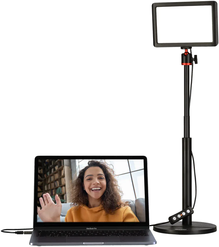 Un ordinateur portable avec une femme à l'écran, une lumière et un trépied.