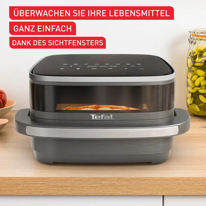 Schwarze Heißluftfritteuse mit Sichtfenster beim Kochen. Text: 'Überwachen Sie Ihr Essen'.