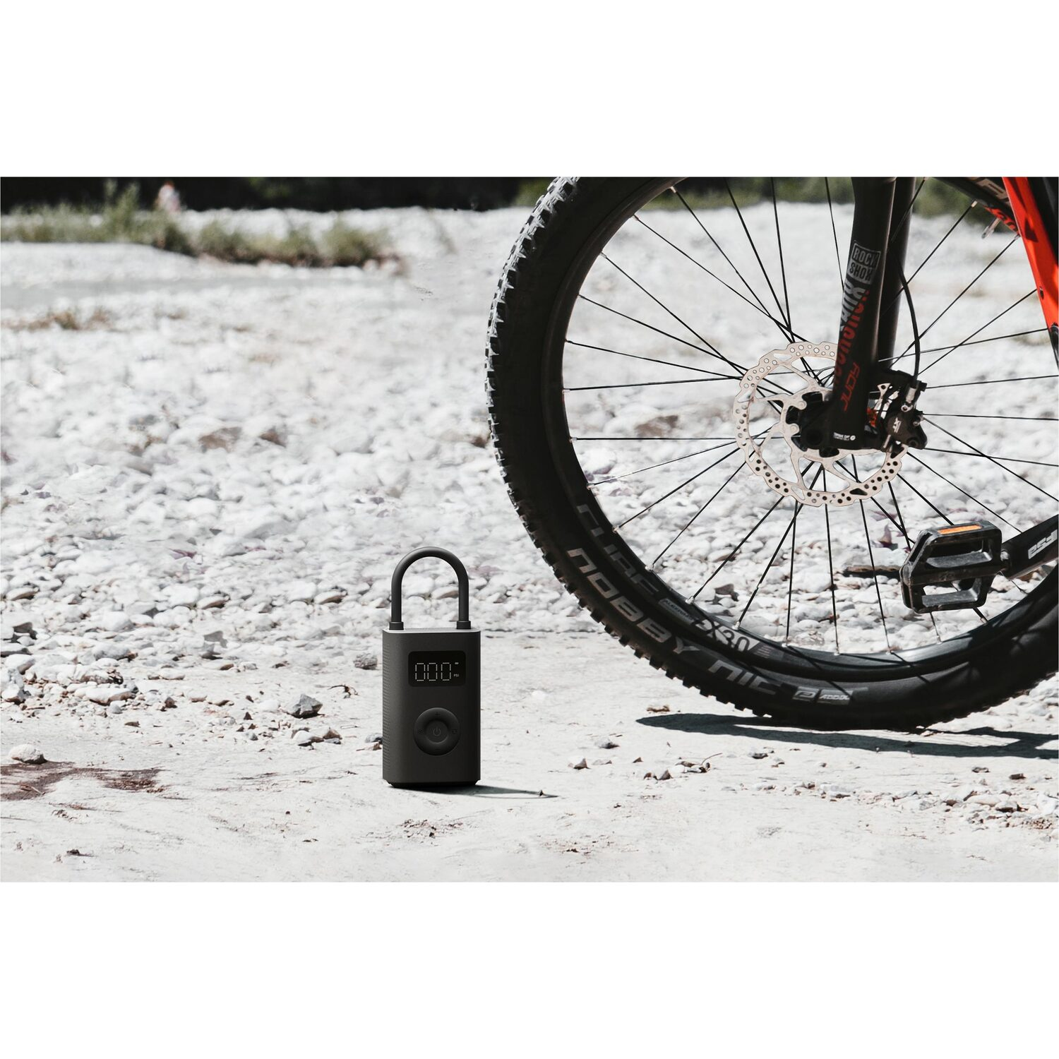 A black tire pump next to a bicycle wheel.