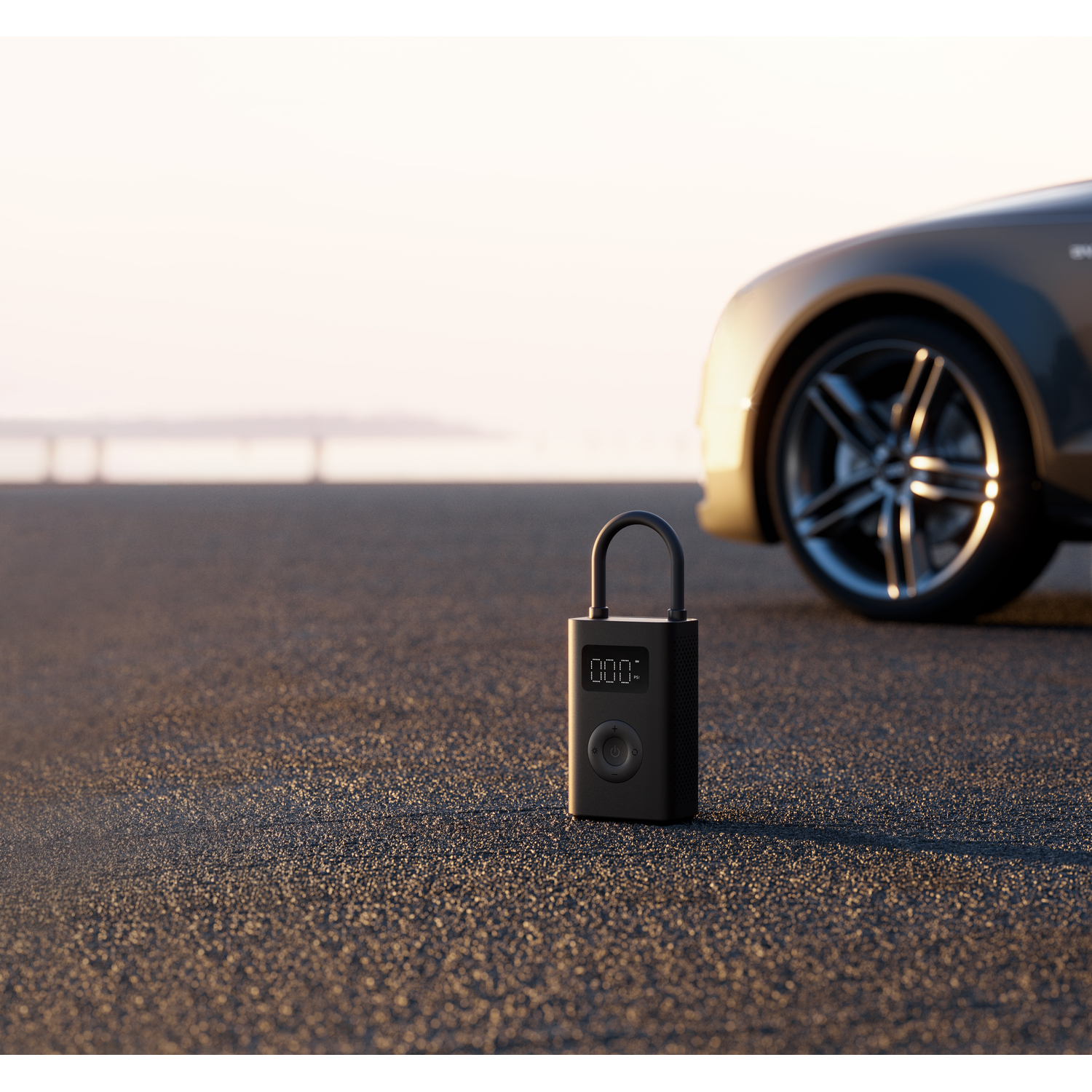 Black air pump with display on asphalt, car in background, sunset.