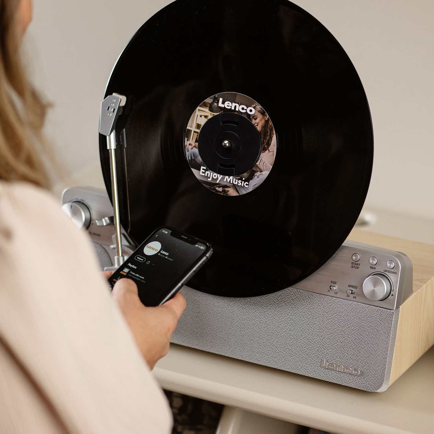 A woman is using a phone near a record player with a vinyl record.