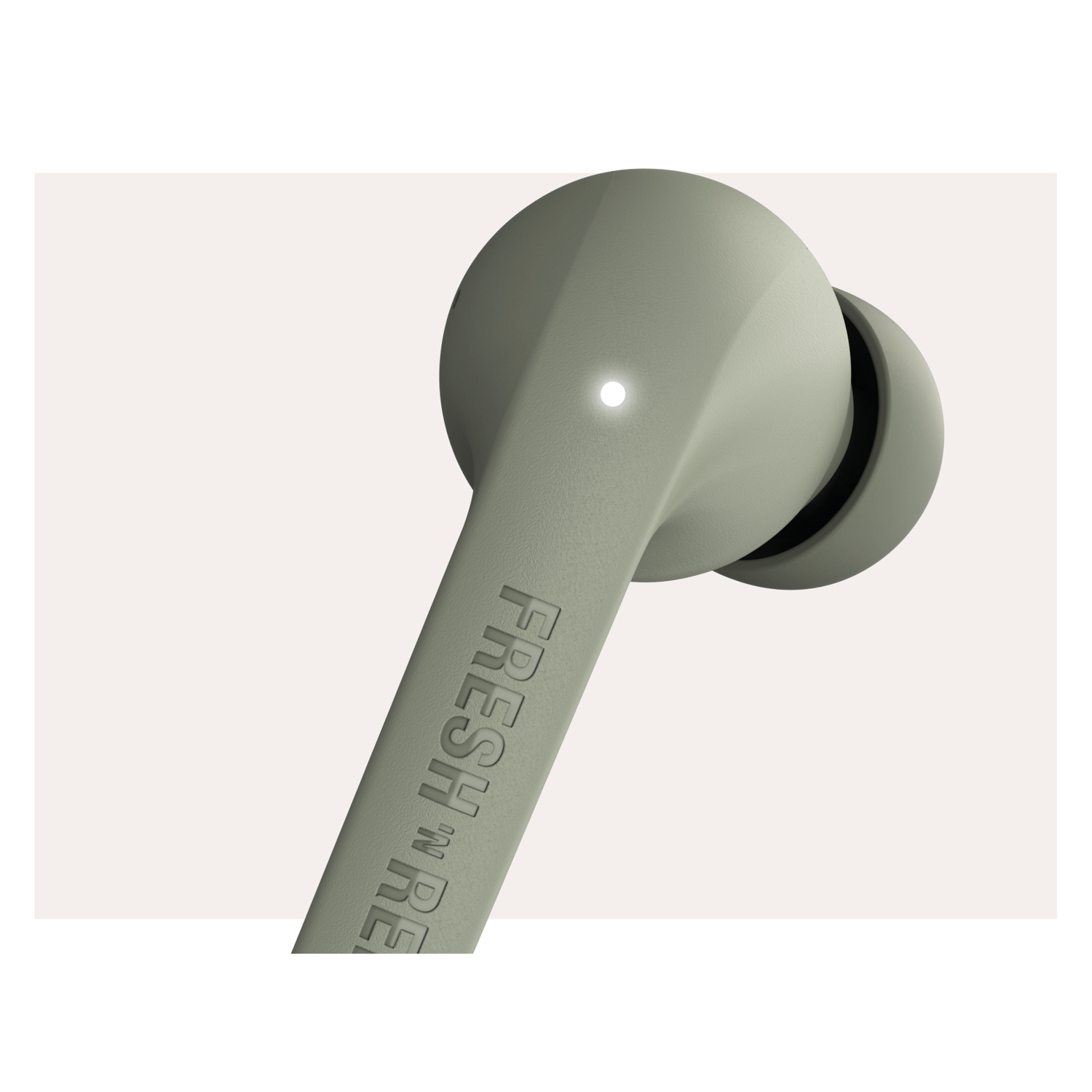 Close-up of a light green wireless earbud with 'FRESH REBEL' printed on it.