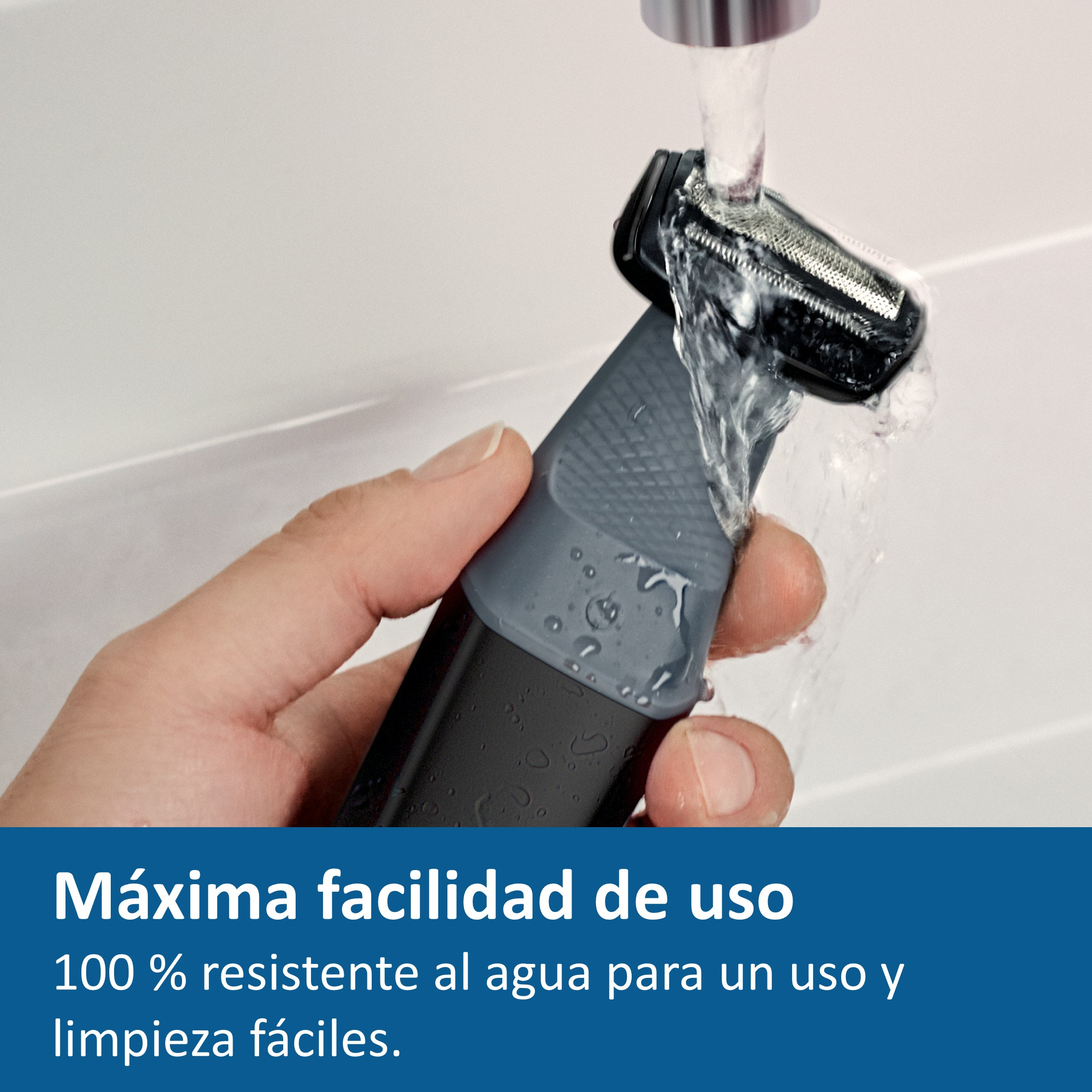 Mano sostiene recortadora bajo agua corriente. Dispositivo negro y gris.