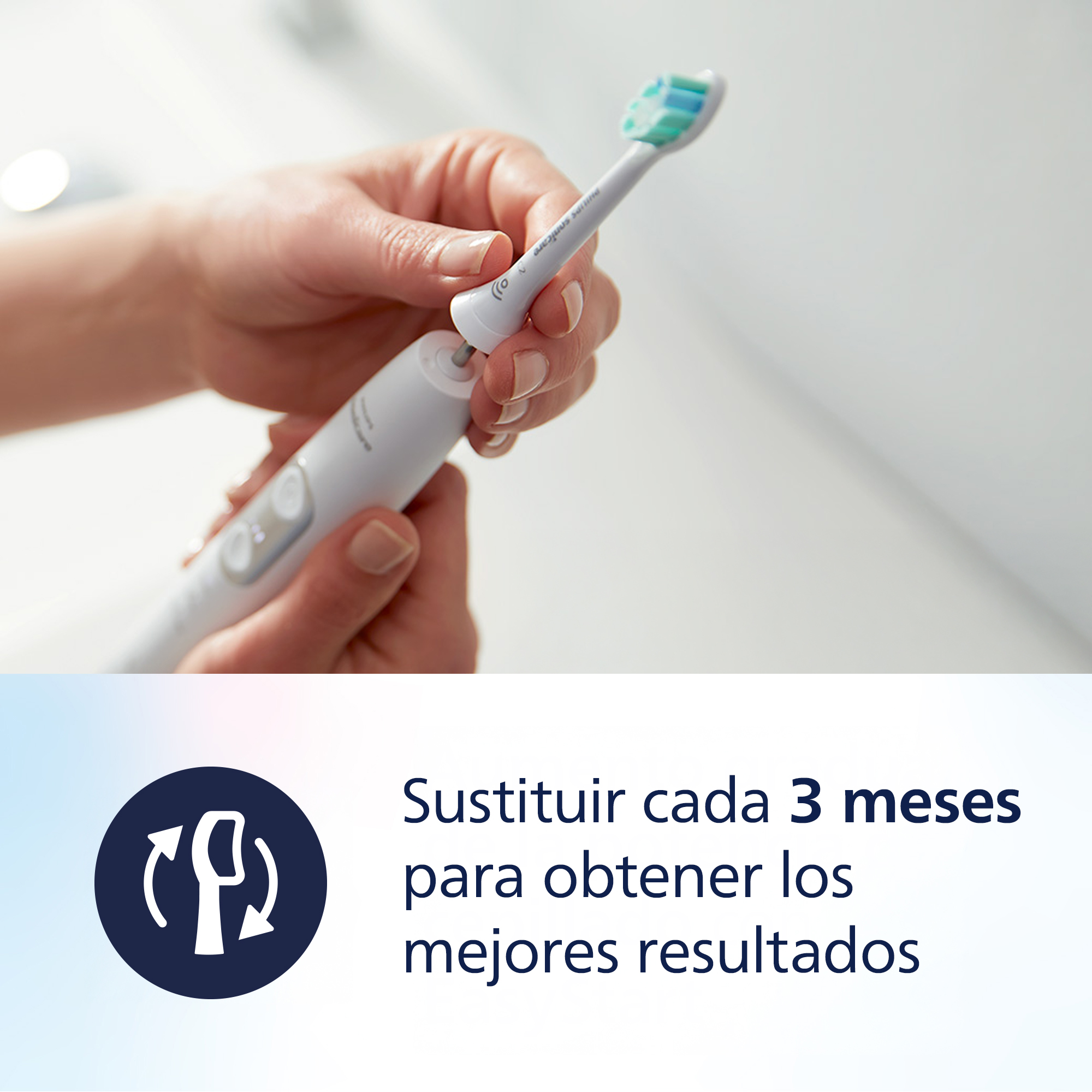 Una mano inserta el cabezal del cepillo en un cepillo de dientes eléctrico blanco.