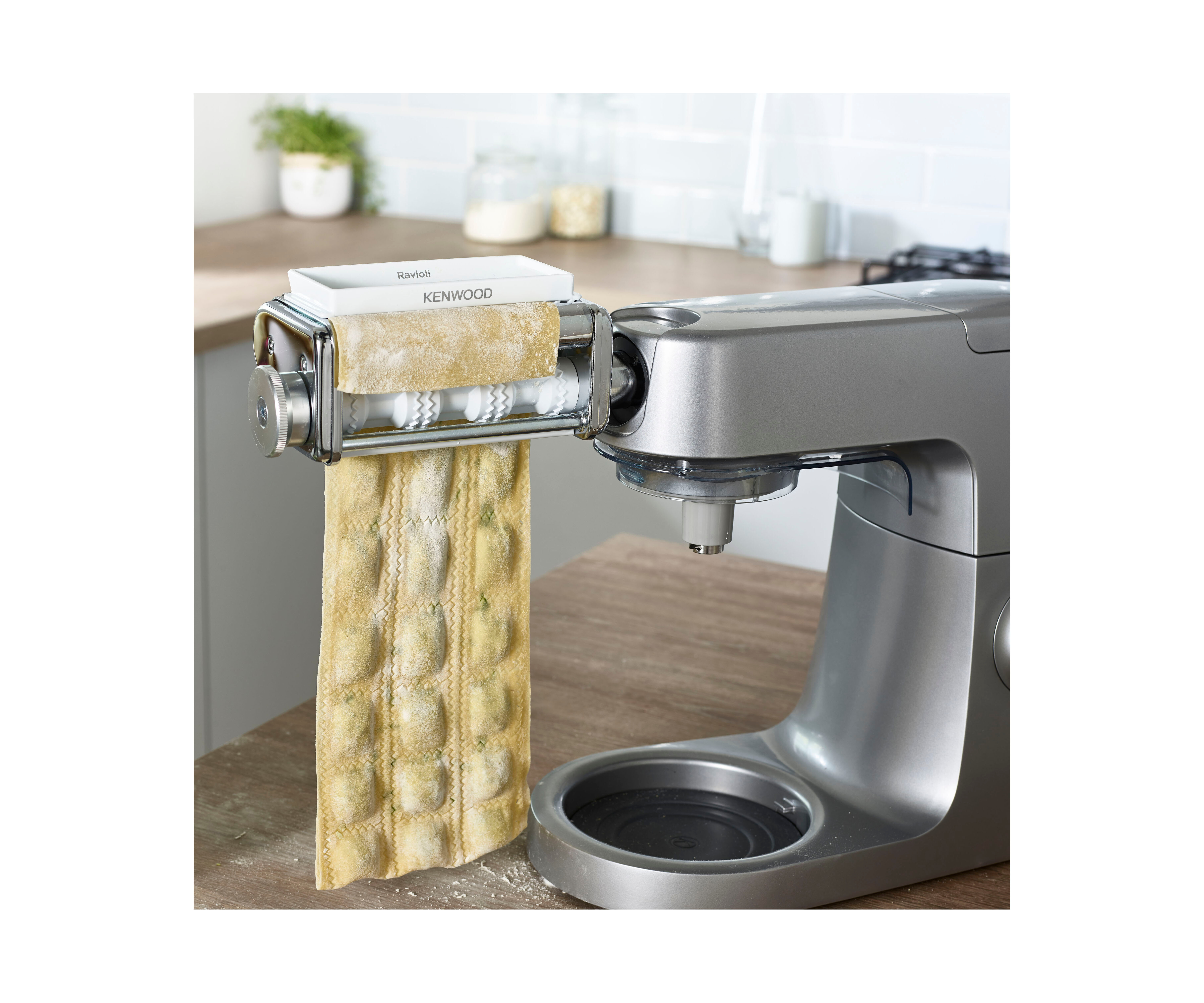 Nudelmaschine mit Ravioli-Aufsatz, beige Ravioli hängen, silberne Maschine.
