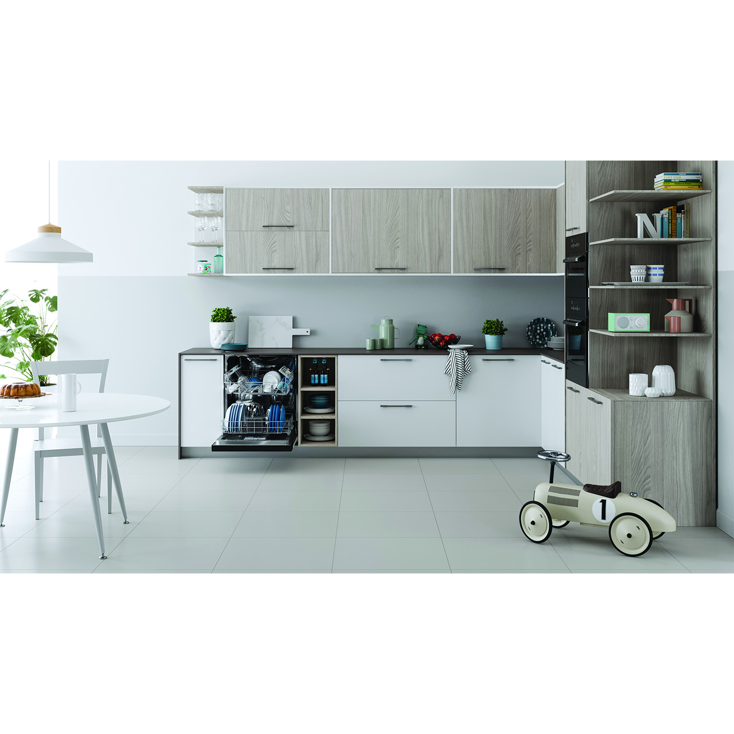 Interno cucina con mobili bianchi e in legno, lavastoviglie aperta, auto giocattolo e tavolo con torta.