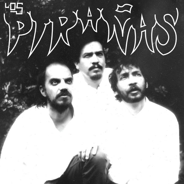 Schwarz-Weiß-Bild. Drei Männer, Los Pirañas, schauen nach oben. Weißer Text darüber.