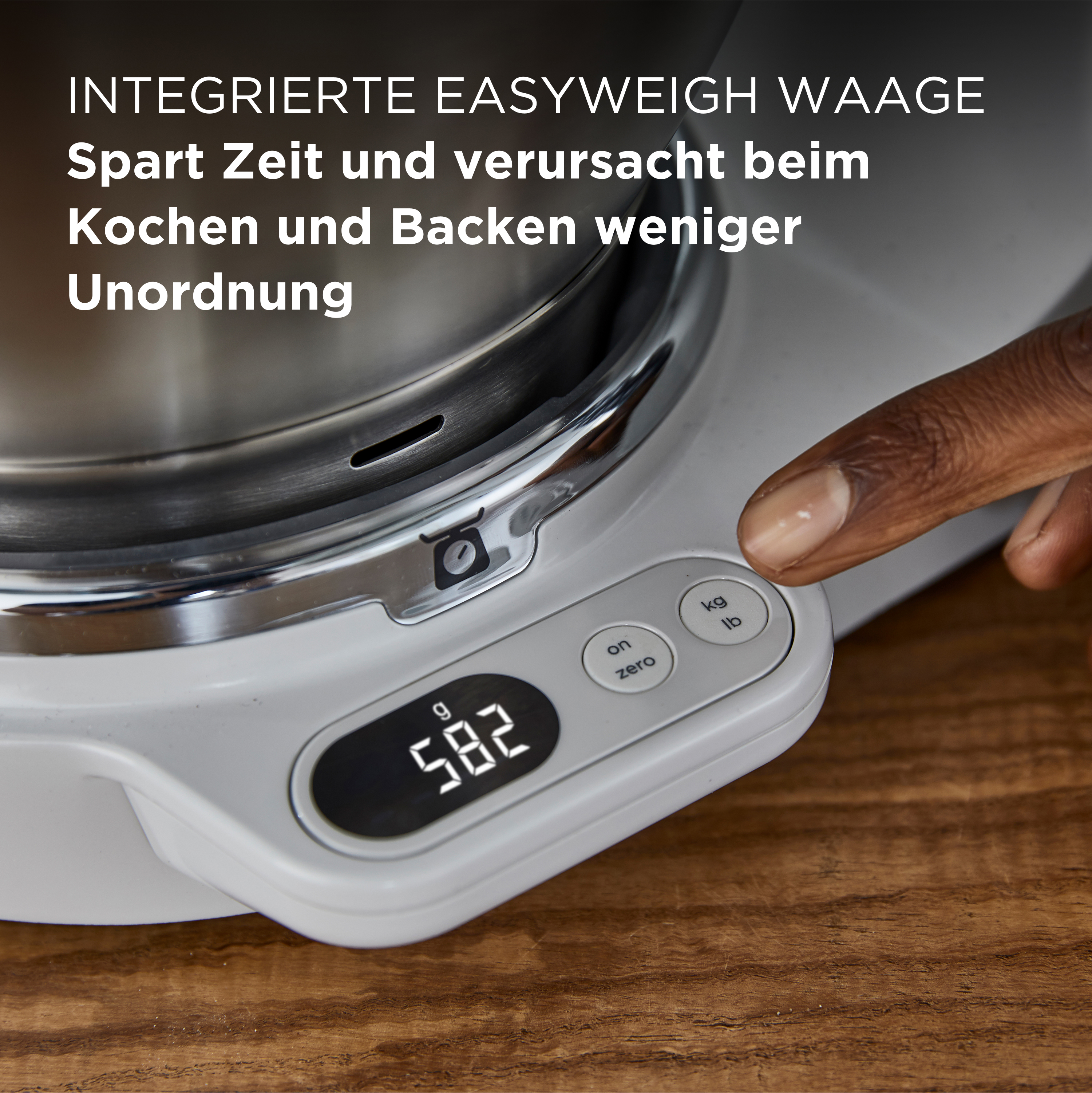 Nahaufnahme einer Küchenwaage. Die Anzeige zeigt 582, und eine Hand drückt die Taste 'on zero'.