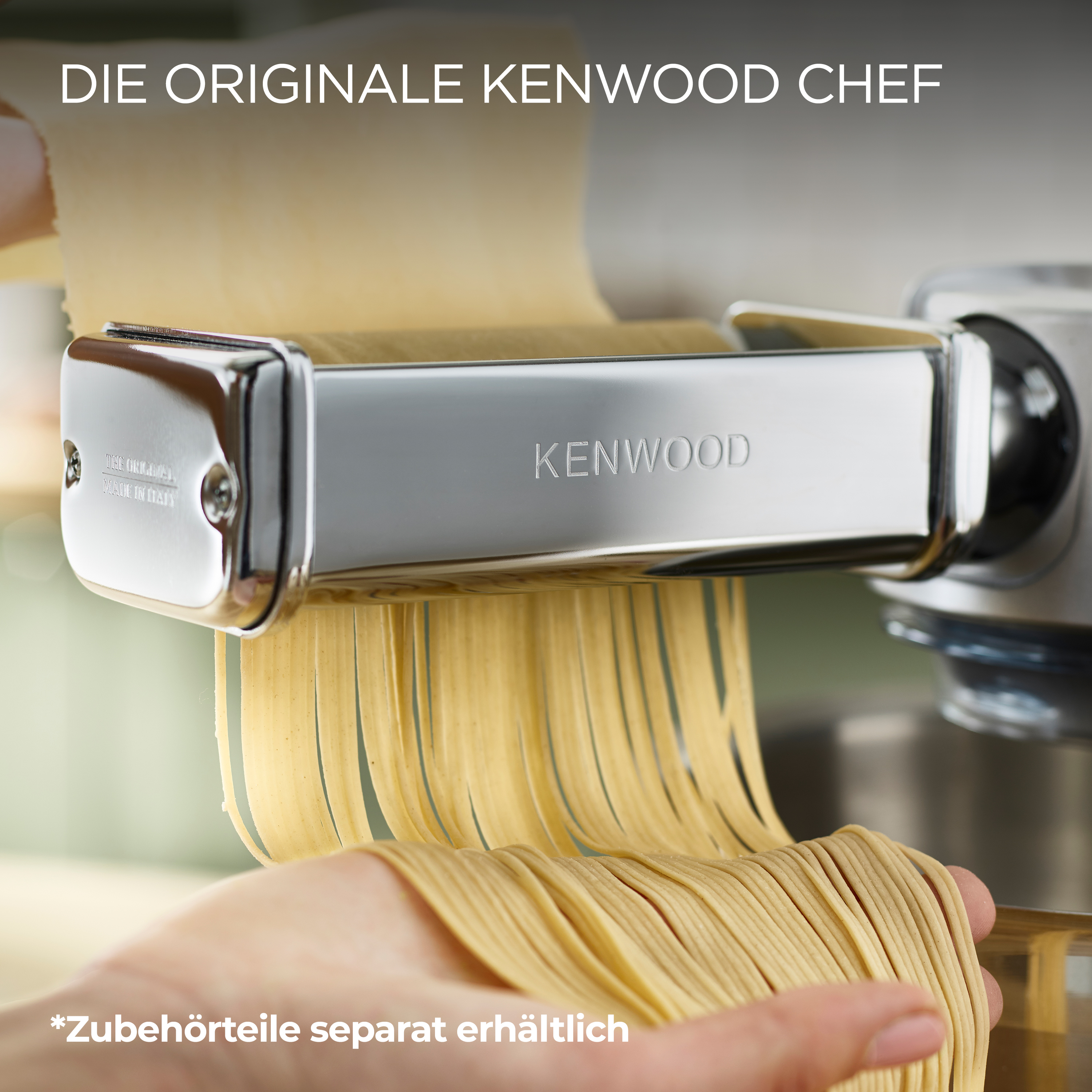 Nudelmaschine mit Nudelsträngen. Kenwood-Markenname sichtbar. Hand greift nach der Pasta.
