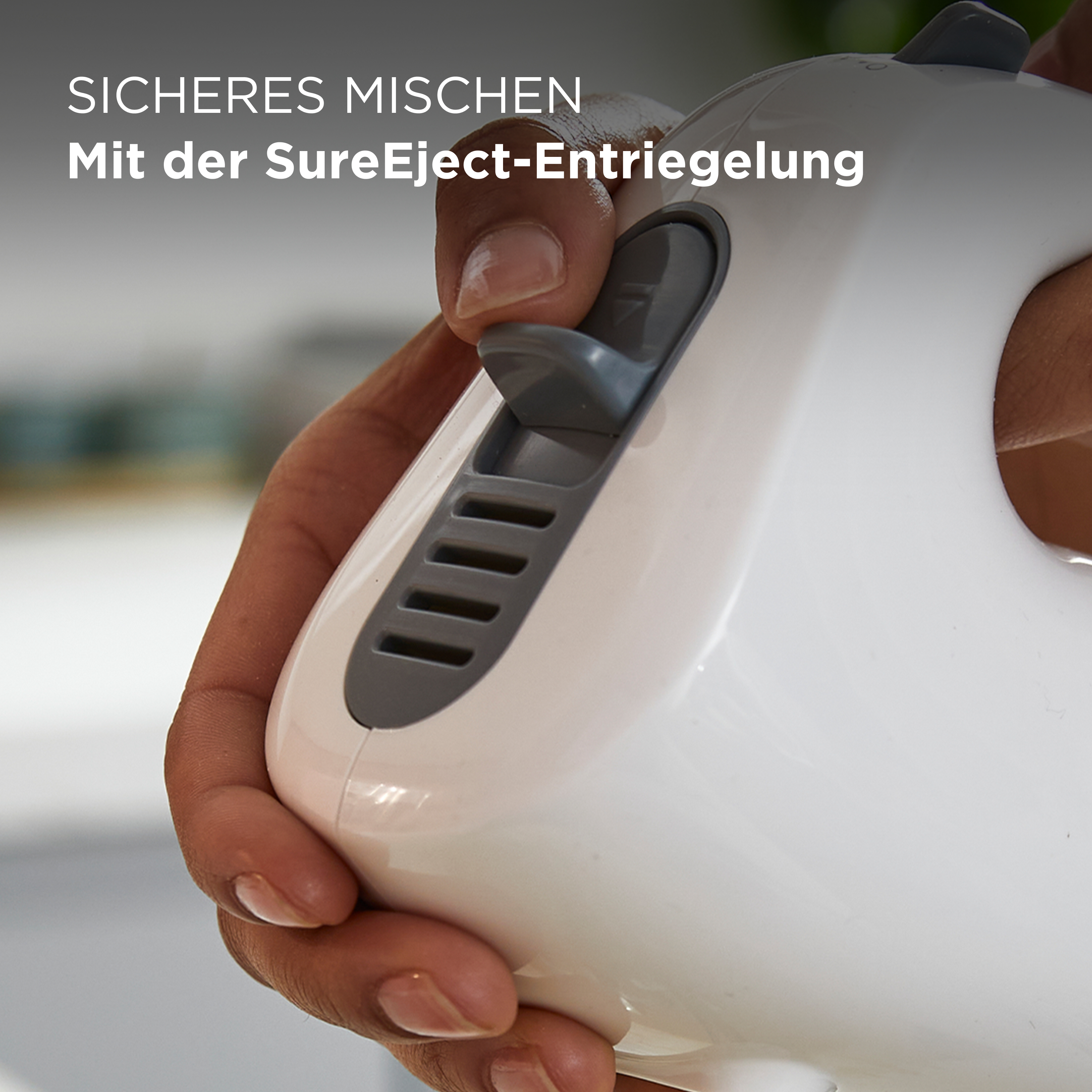 Nahaufnahme einer Hand, die einen Knopf an einem weißen Handmixer drückt.