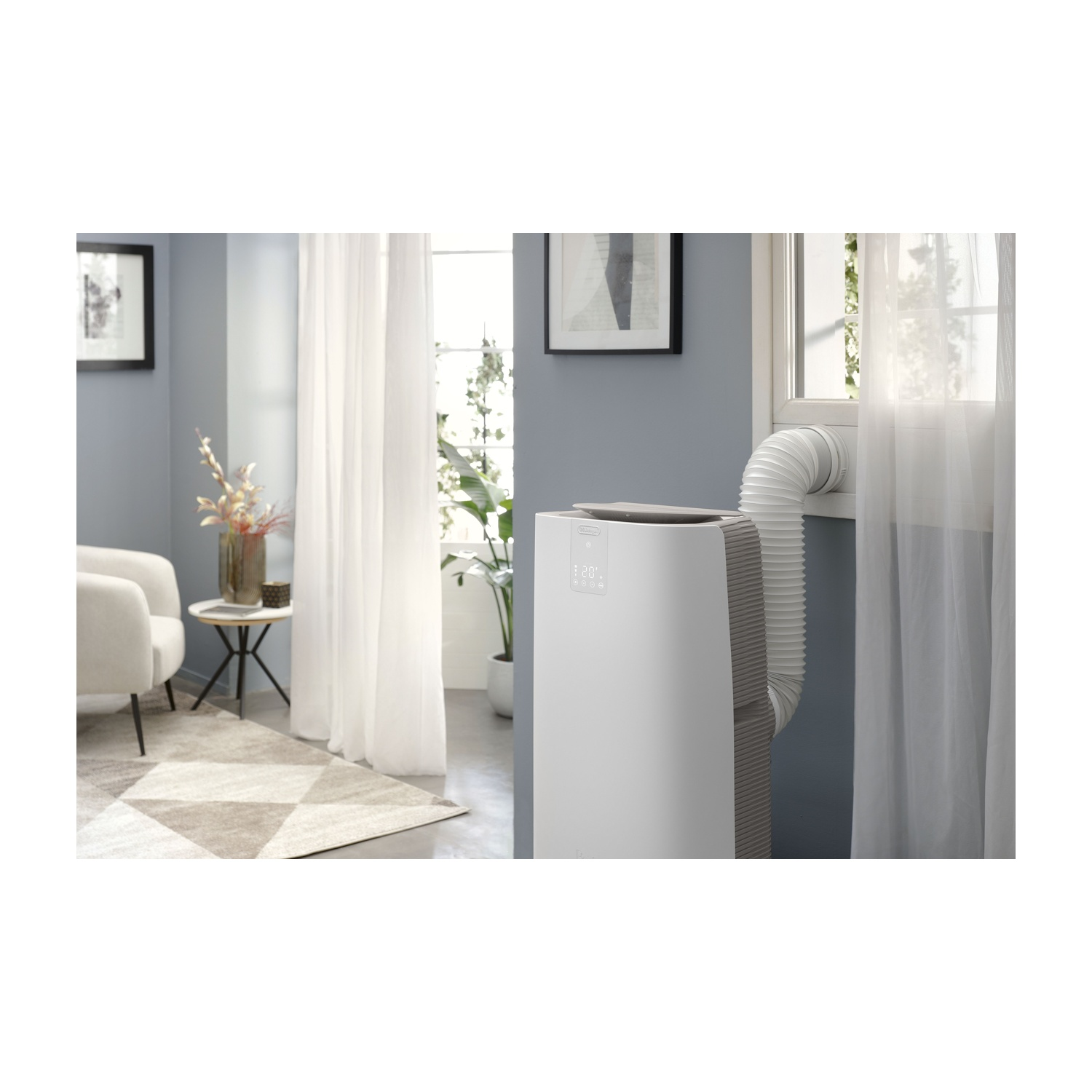Condizionatore bianco con tubo di scarico flessibile vicino a una finestra. Interno.