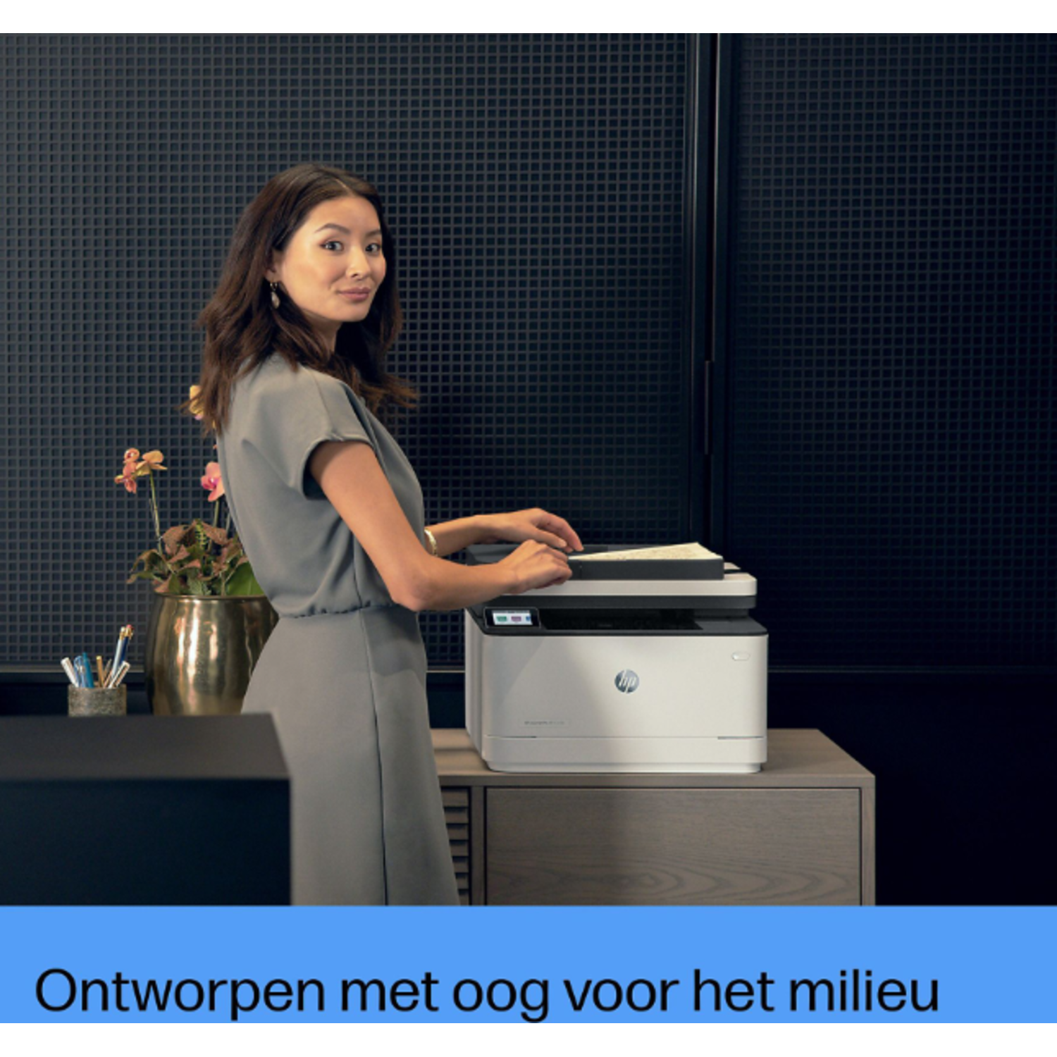 Woman using a white HP printer in an office setting with a gold pot and plant. 