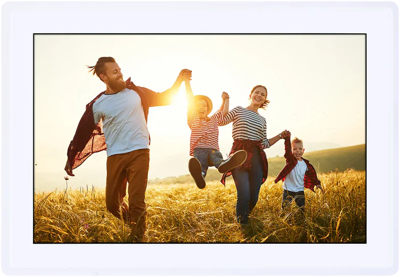 Une famille de quatre personnes court joyeusement à travers un champ, se tenant par la main, le soleil se couchant.