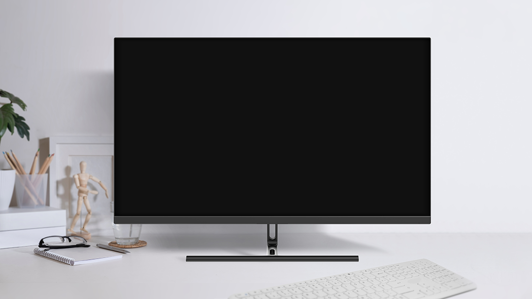 Számítógép monitor fehér asztalon. Billentyűzet, jegyzetfüzet és szemüveg látható.