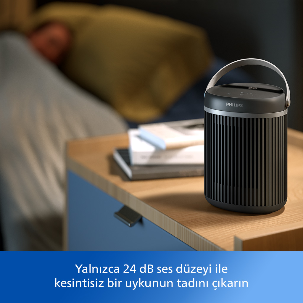 Yatakta uyuyan bir kişiyle birlikte komodinde siyah bir hava temizleyici.