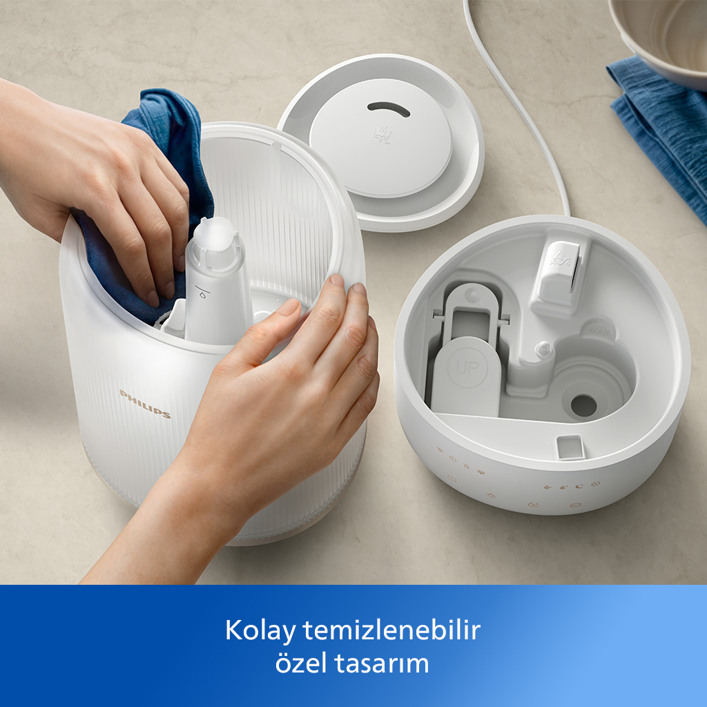 Eller beyaz bir nemlendiriciyi temizliyor. Parçalar ayrılmış. Mavi bez mevcut. Yukarıdan görünüm.