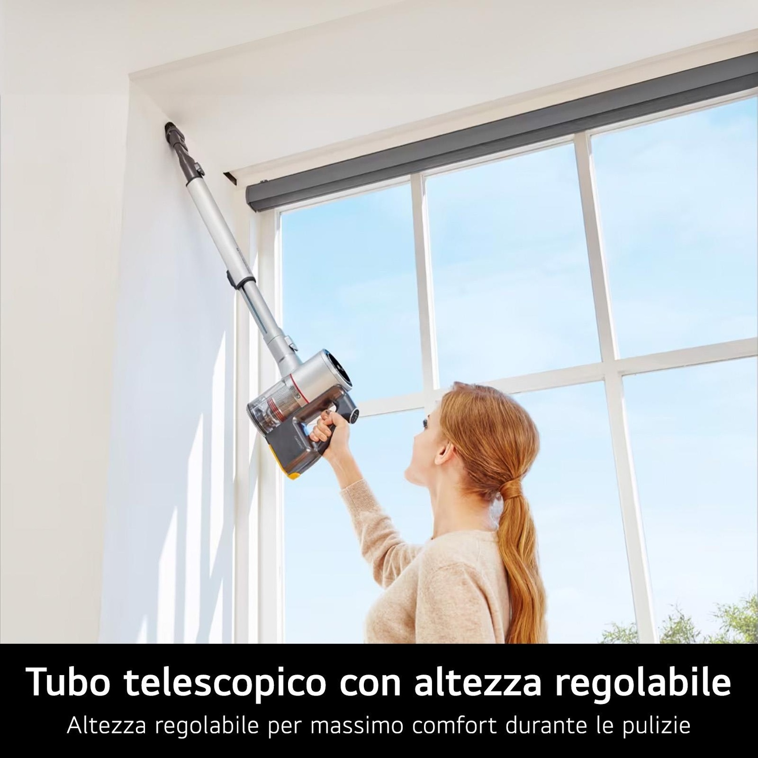 Donna usa un aspirapolvere portatile per pulire un telaio di finestra, una finestra sullo sfondo.